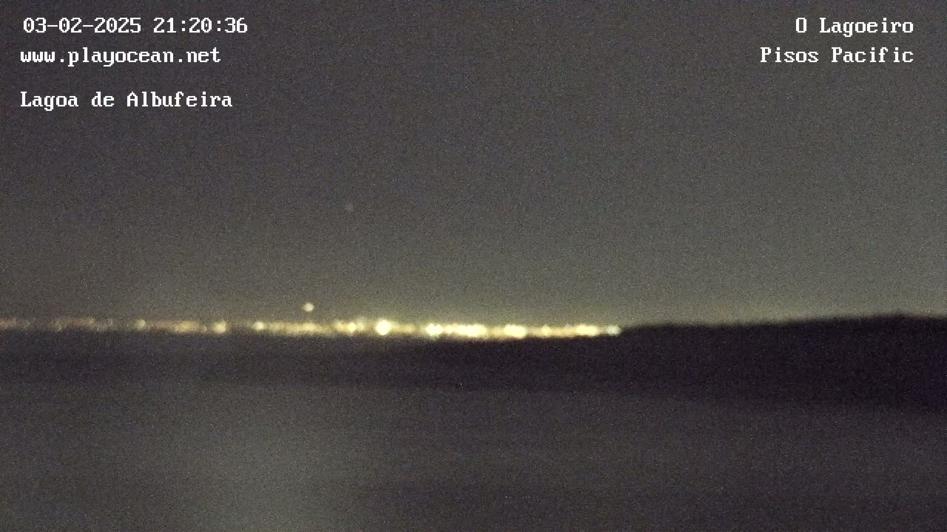 A nighttime, long-distance view of a distant city skyline illuminated by lights, under a dark sky.