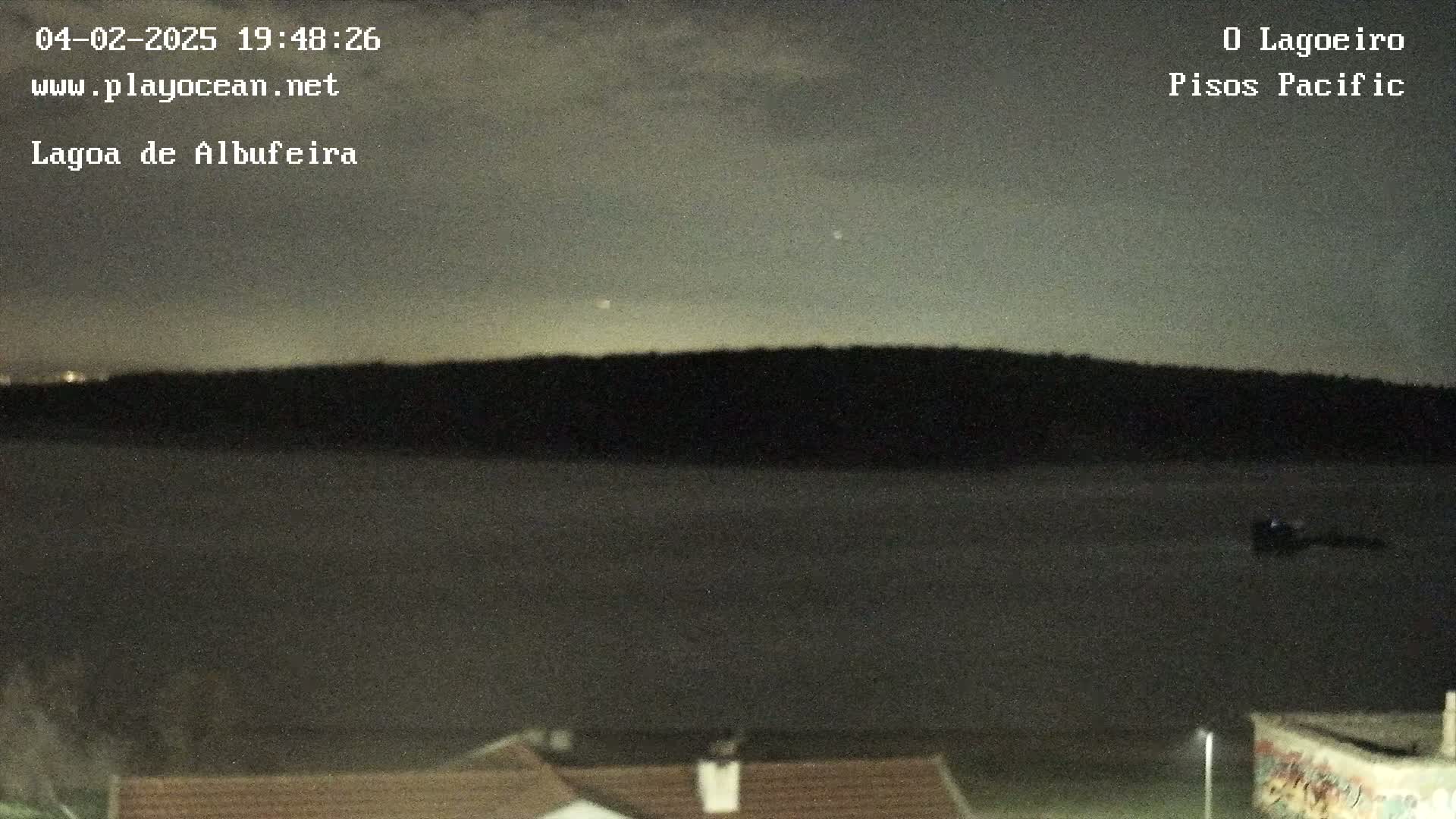 A dark body of water is visible under a night sky with a few faint stars, and a dark landmass is seen in the distance.
