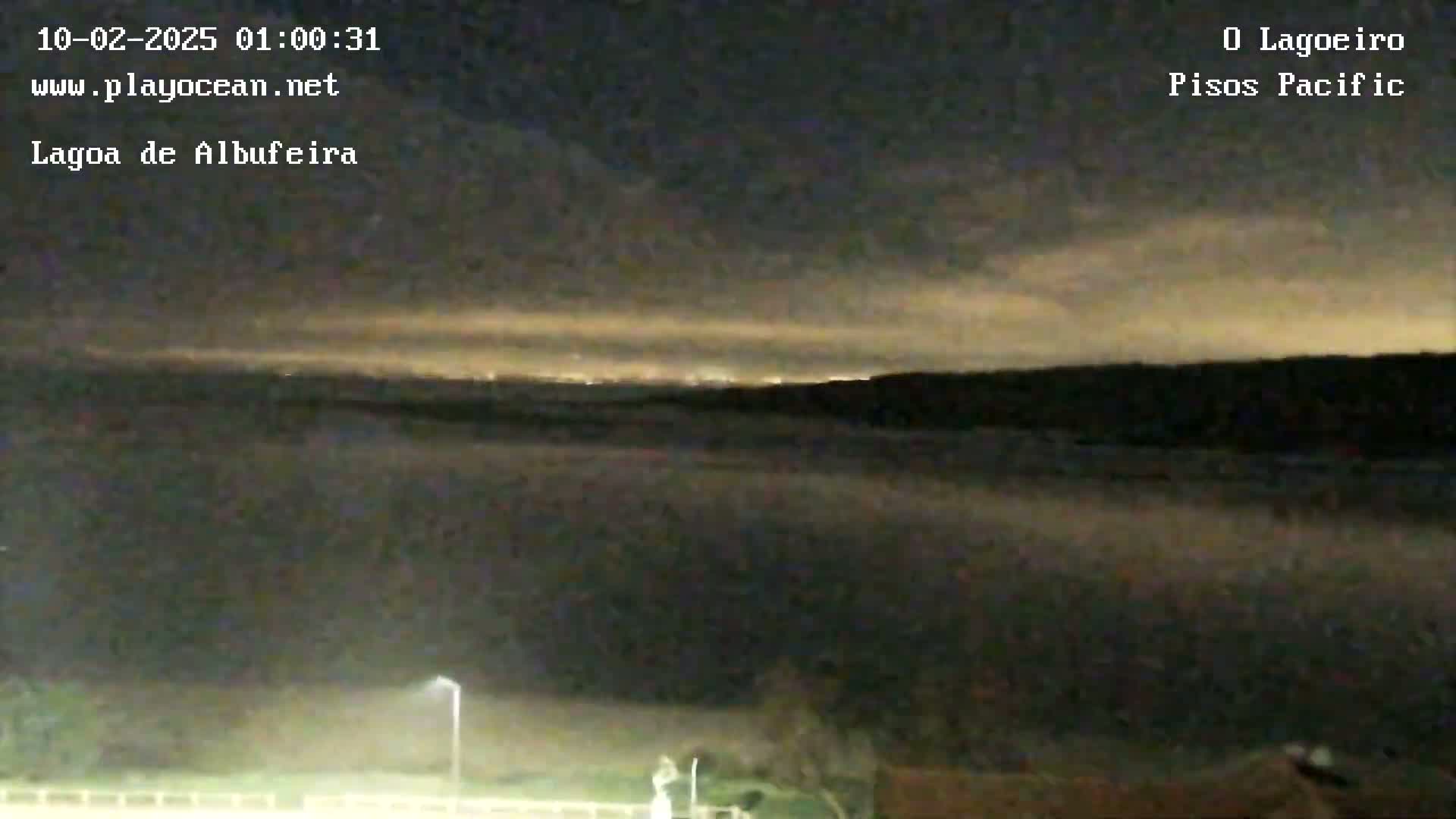 A nighttime, hazy view of a body of water with distant lights and a dark, cloudy sky.