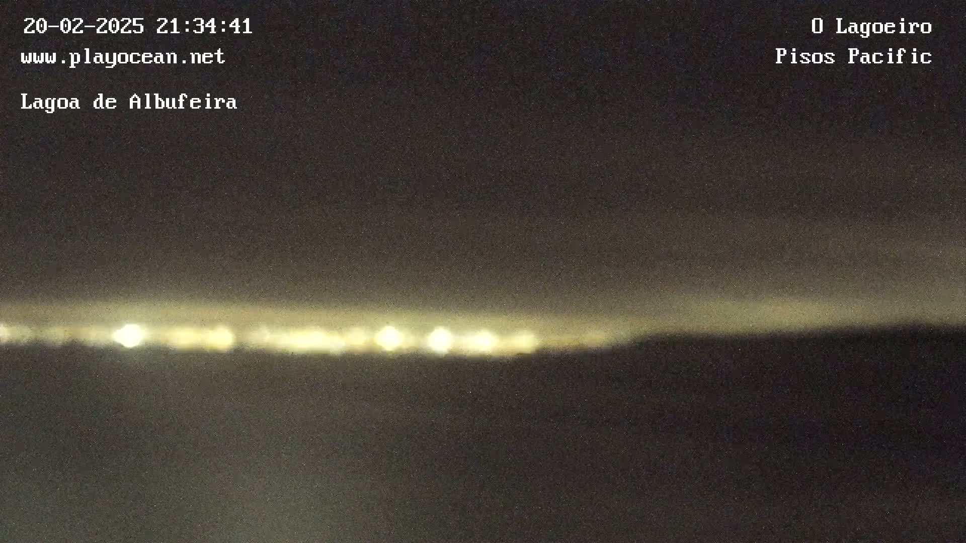 A nighttime, blurry long shot shows a line of distant lights on the horizon under a dark sky.