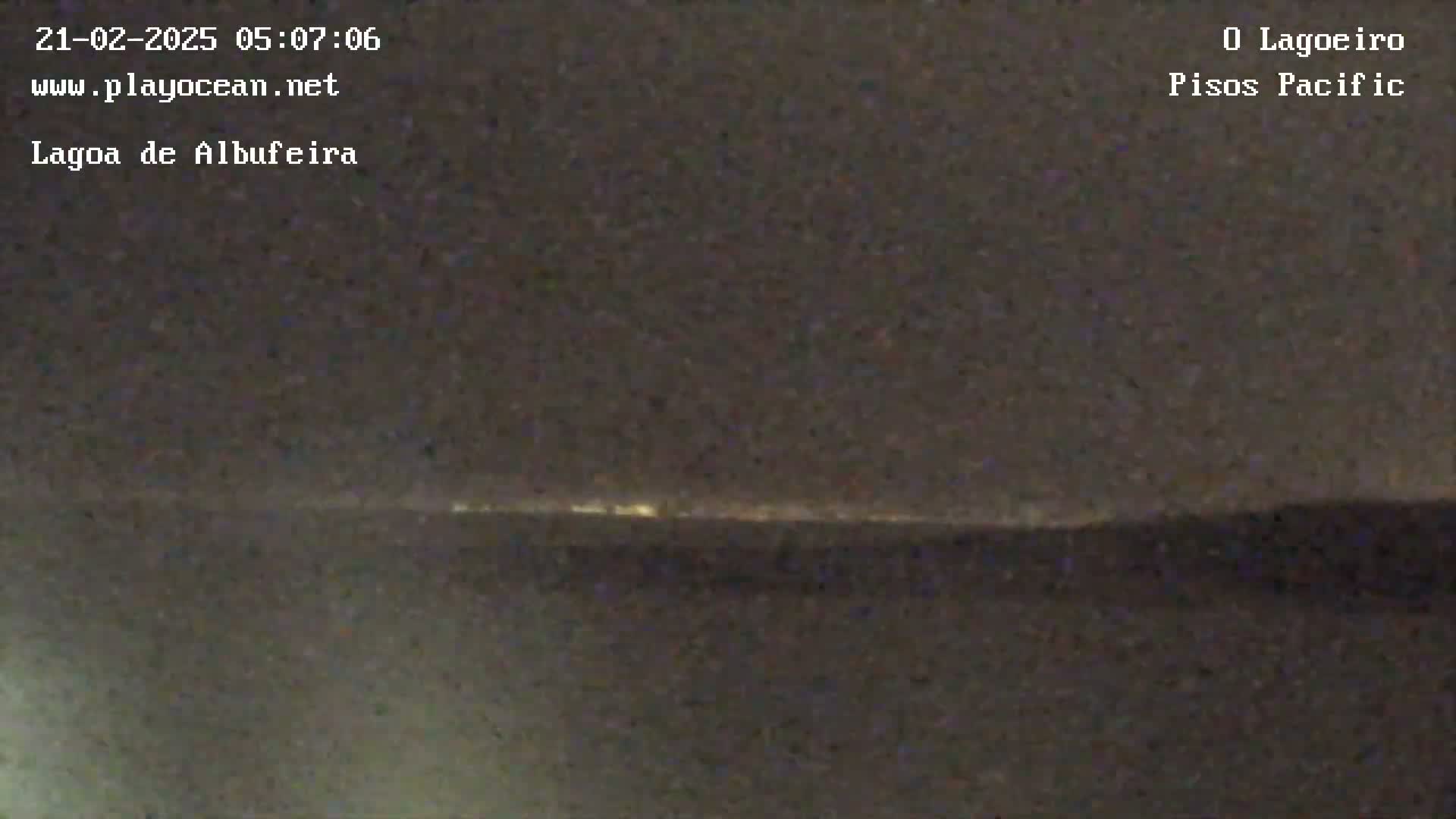 A nighttime, low-light view shows a distant line of lights on the horizon.