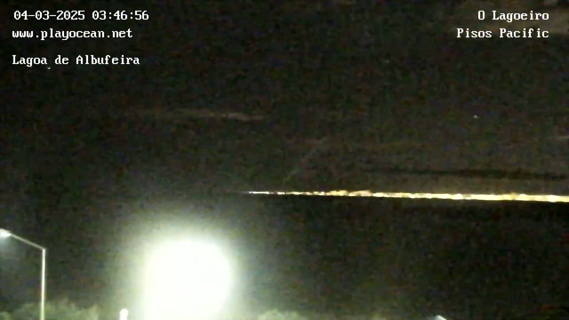 A nighttime long-exposure shot shows a line of lights on the horizon under a dark, mostly clear sky.