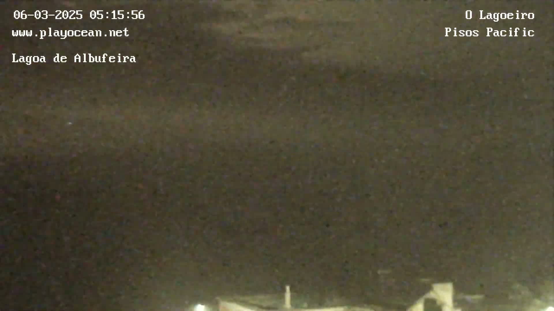 A dark, nighttime scene shows a mostly obscured view of a body of water under a cloudy sky.