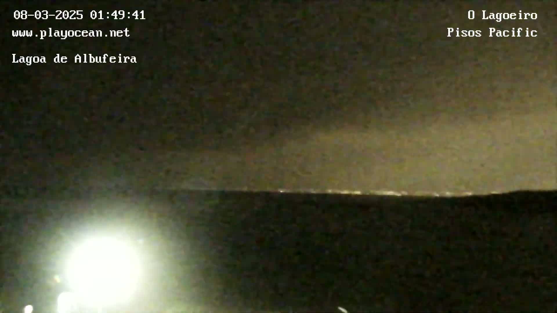 A nighttime long shot shows a dark landscape with a faint line of lights on the horizon under a cloudy sky.