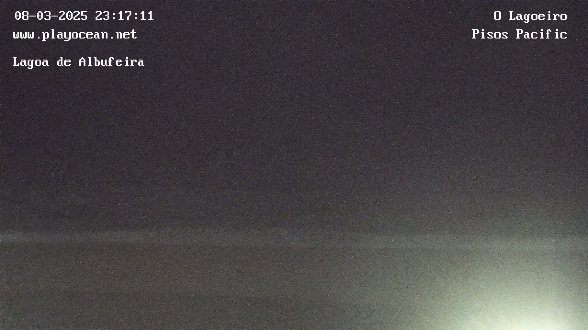 A dark, nighttime view of a body of water with a faint, light glow on the horizon.