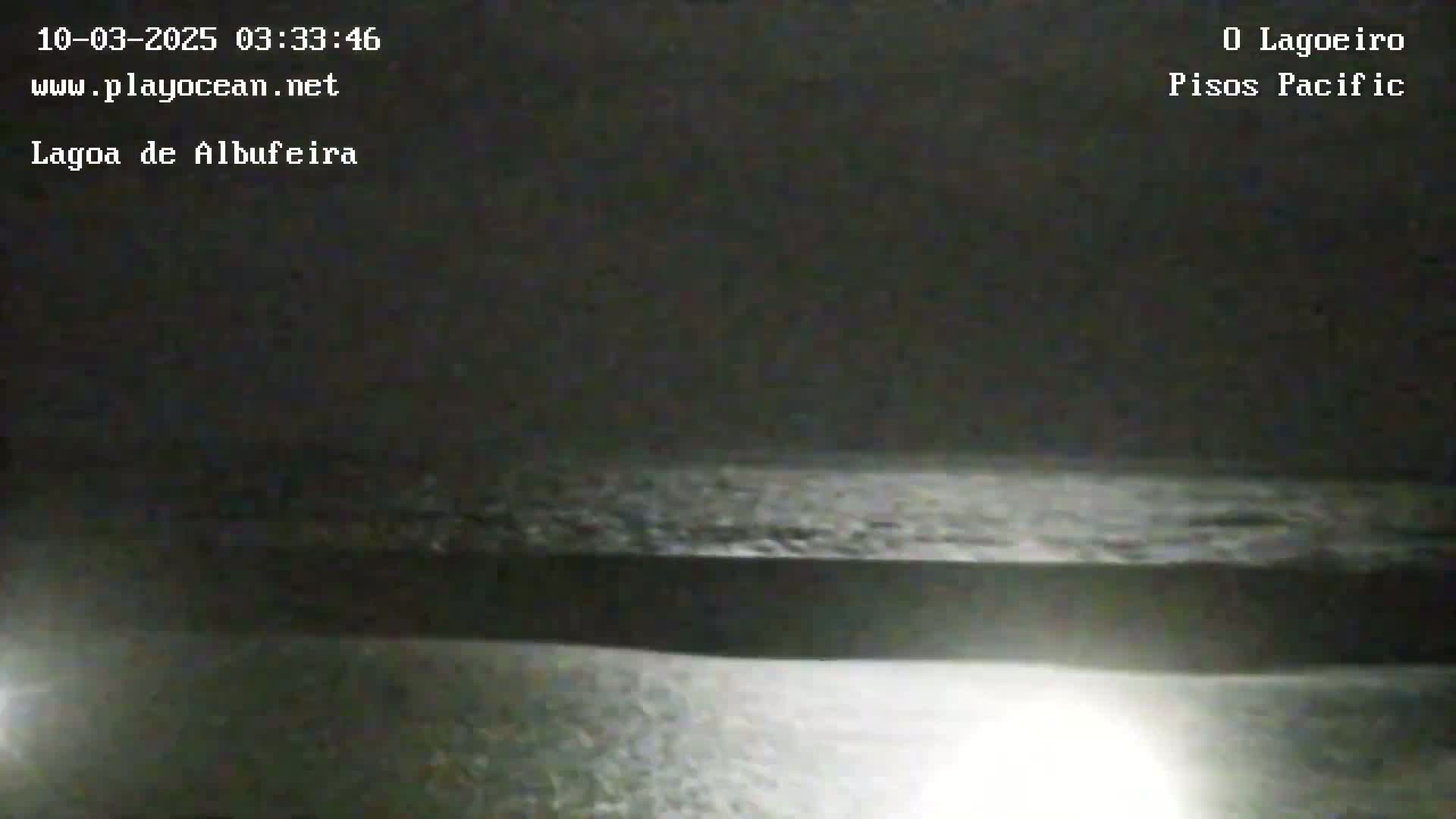 A dark, nighttime scene shows a body of water under an overcast sky.