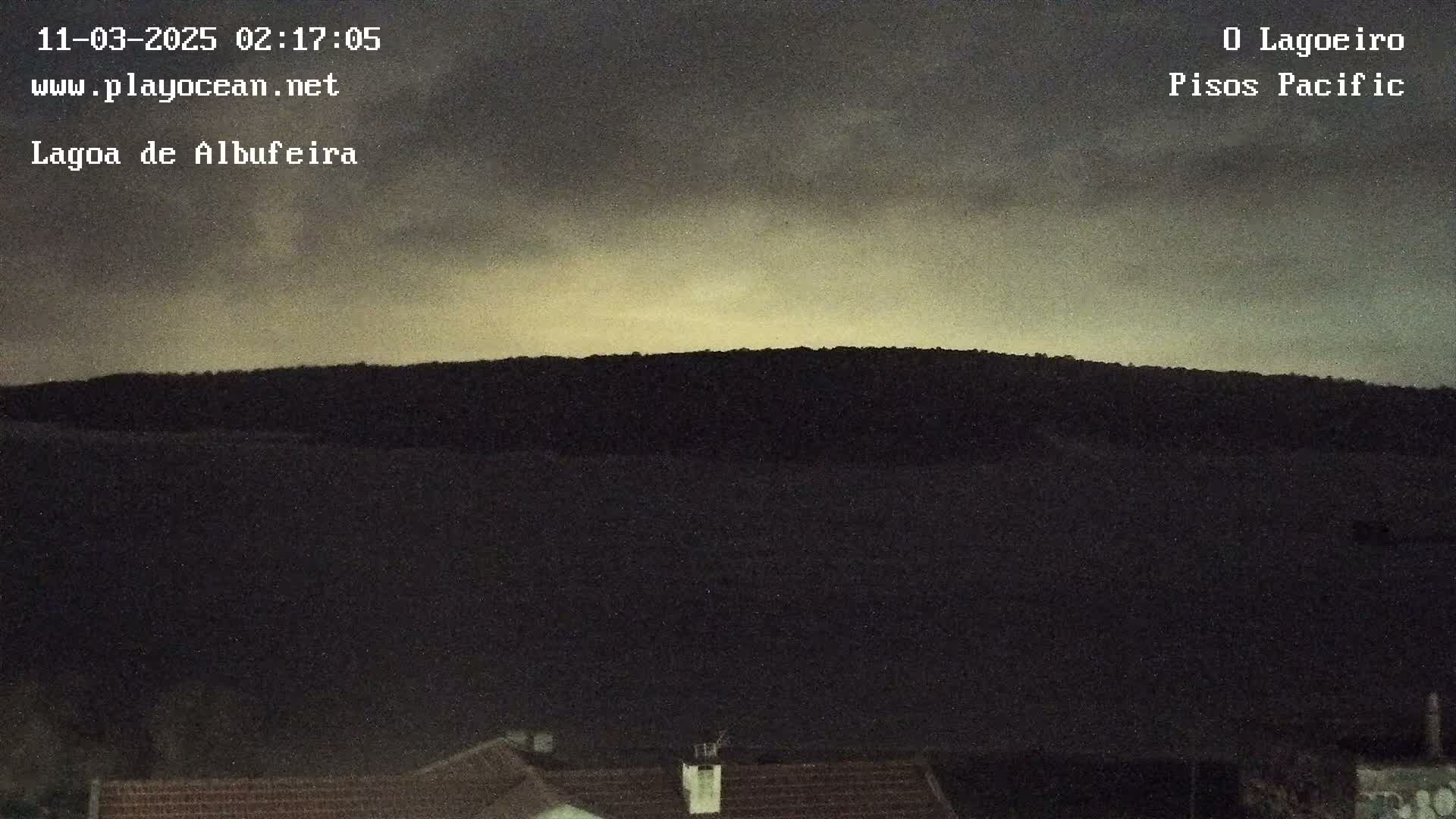 A dark hill is silhouetted against a twilight sky with overcast conditions.