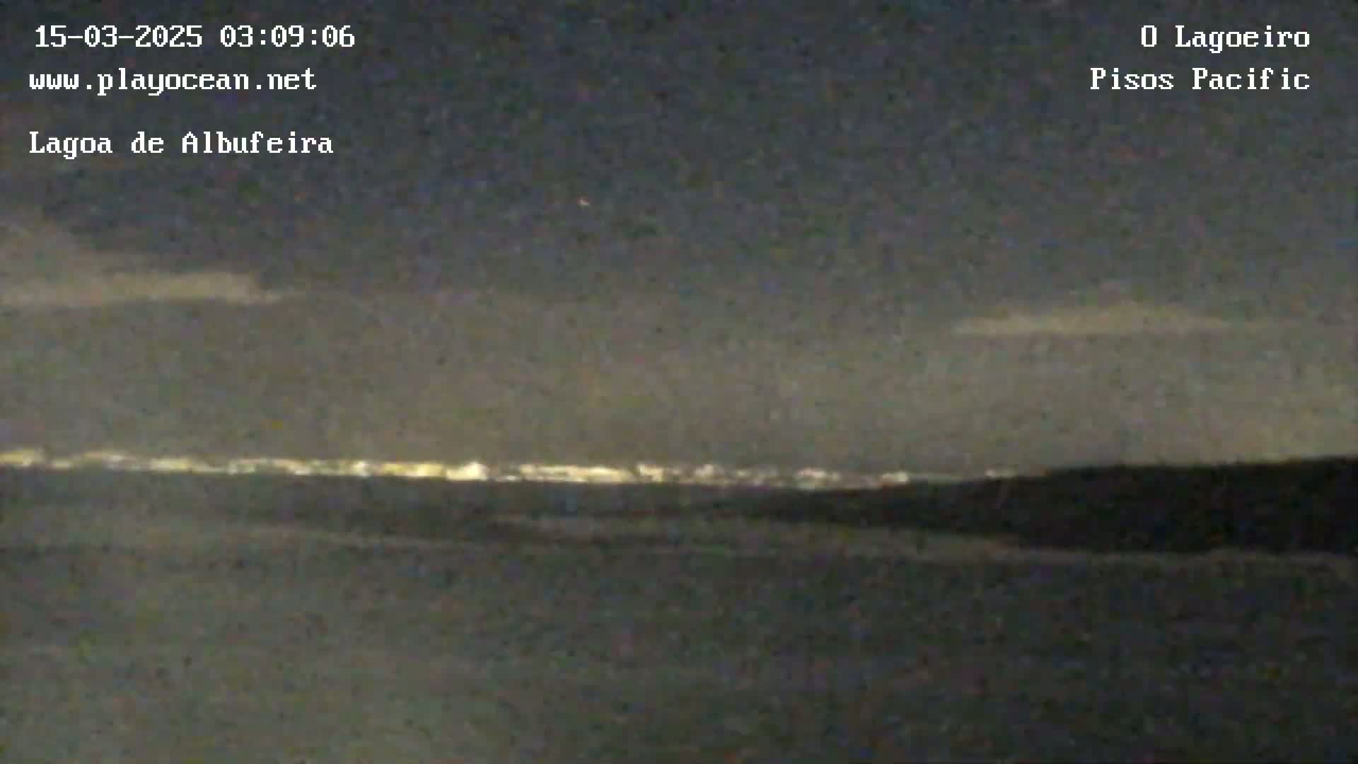 A nighttime long shot shows a dark landscape with a distant line of city lights under a mostly clear, dark sky.