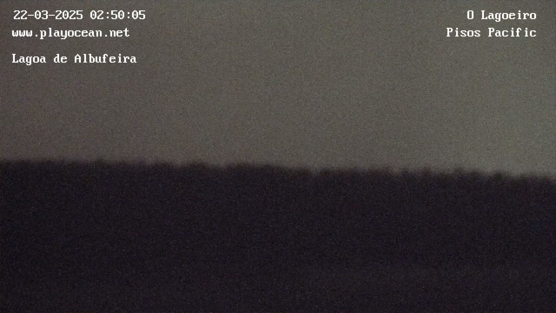 A dark, possibly nighttime, image shows a flat horizon line separating a slightly lighter gray sky from a very dark, indistinct land mass.