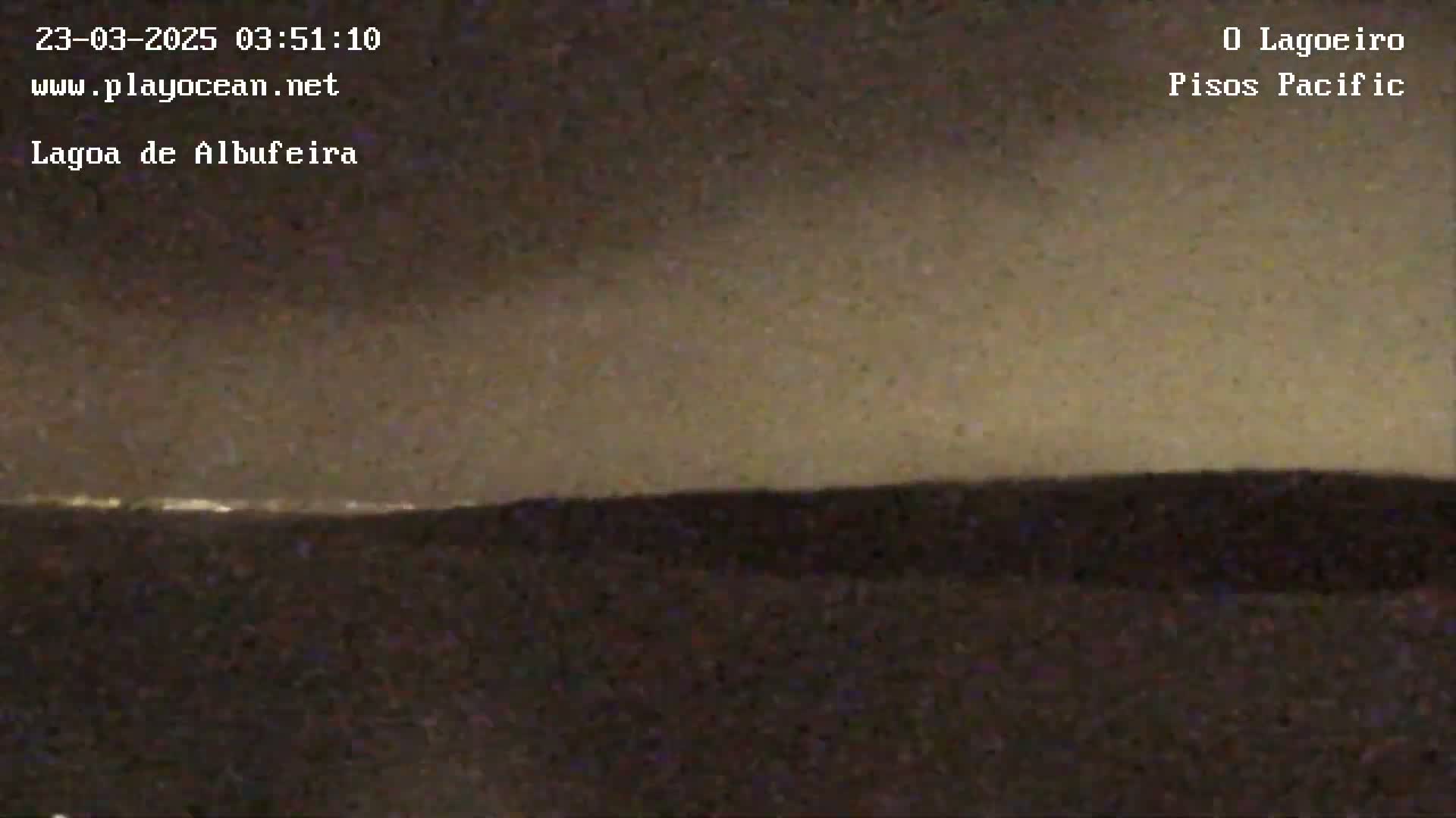 A nighttime long shot shows a dark landscape with a faint line of lights on the horizon under a cloudy, dusky sky.
