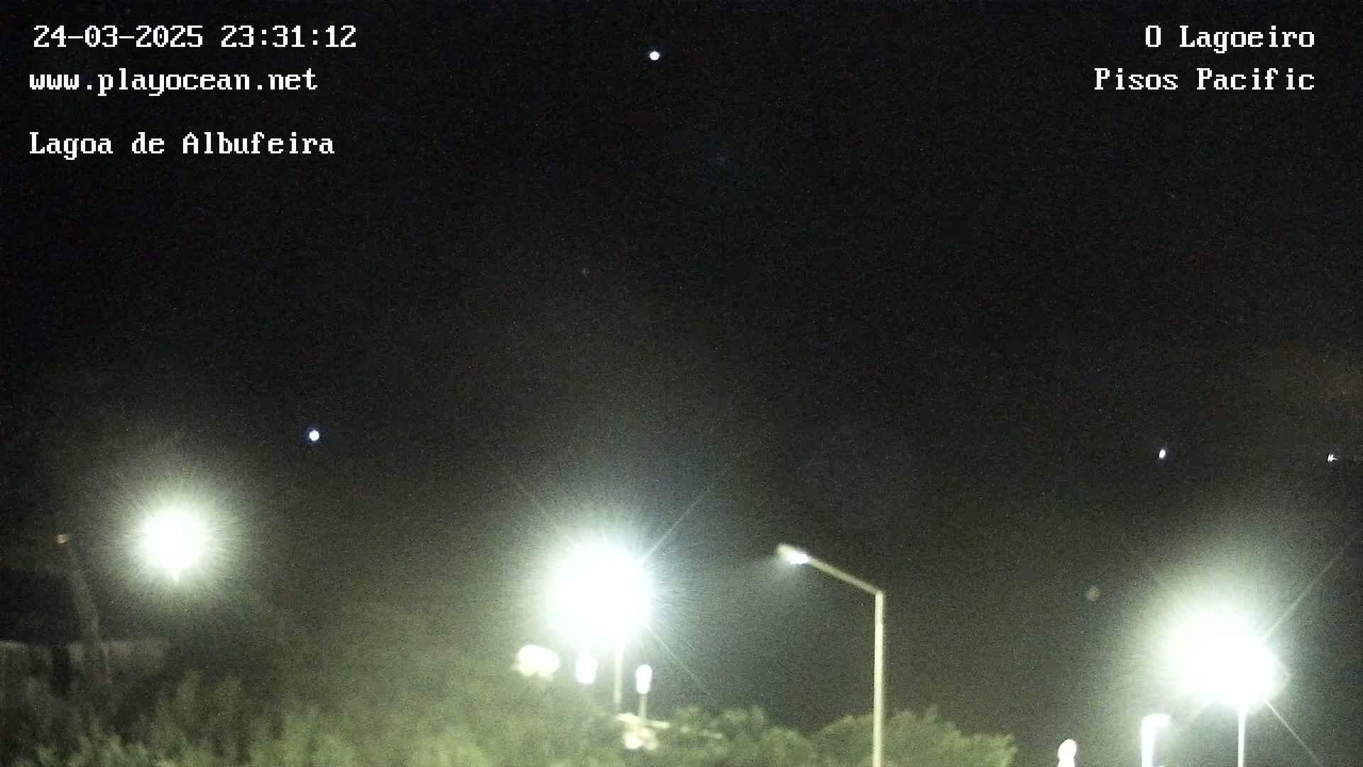 Brightly lit streetlights illuminate a dark night sky speckled with a few visible stars.