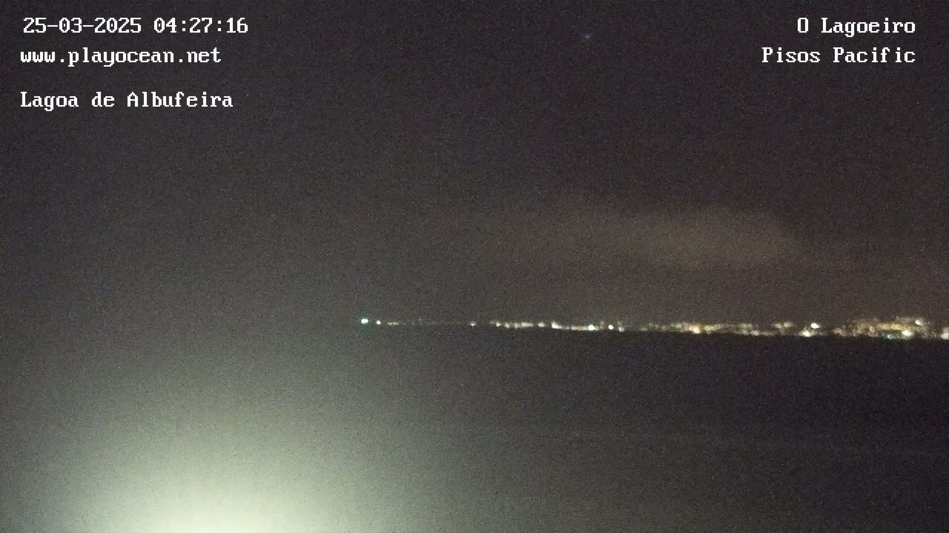 A nighttime long shot shows a distant line of lights on the horizon under a dark, mostly clear sky.