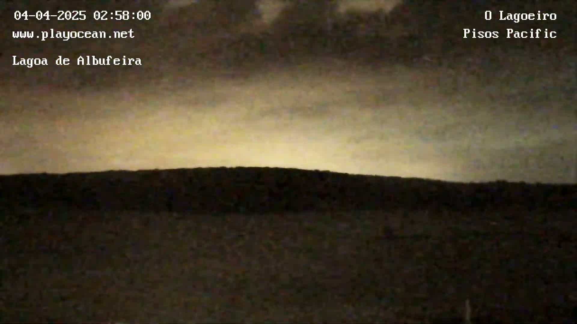 A dark, flat landscape is visible under a pale, cloudy sky, possibly at dawn or dusk.