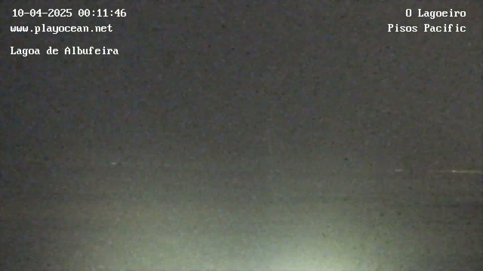 A dark, nighttime view of a body of water under an overcast sky.