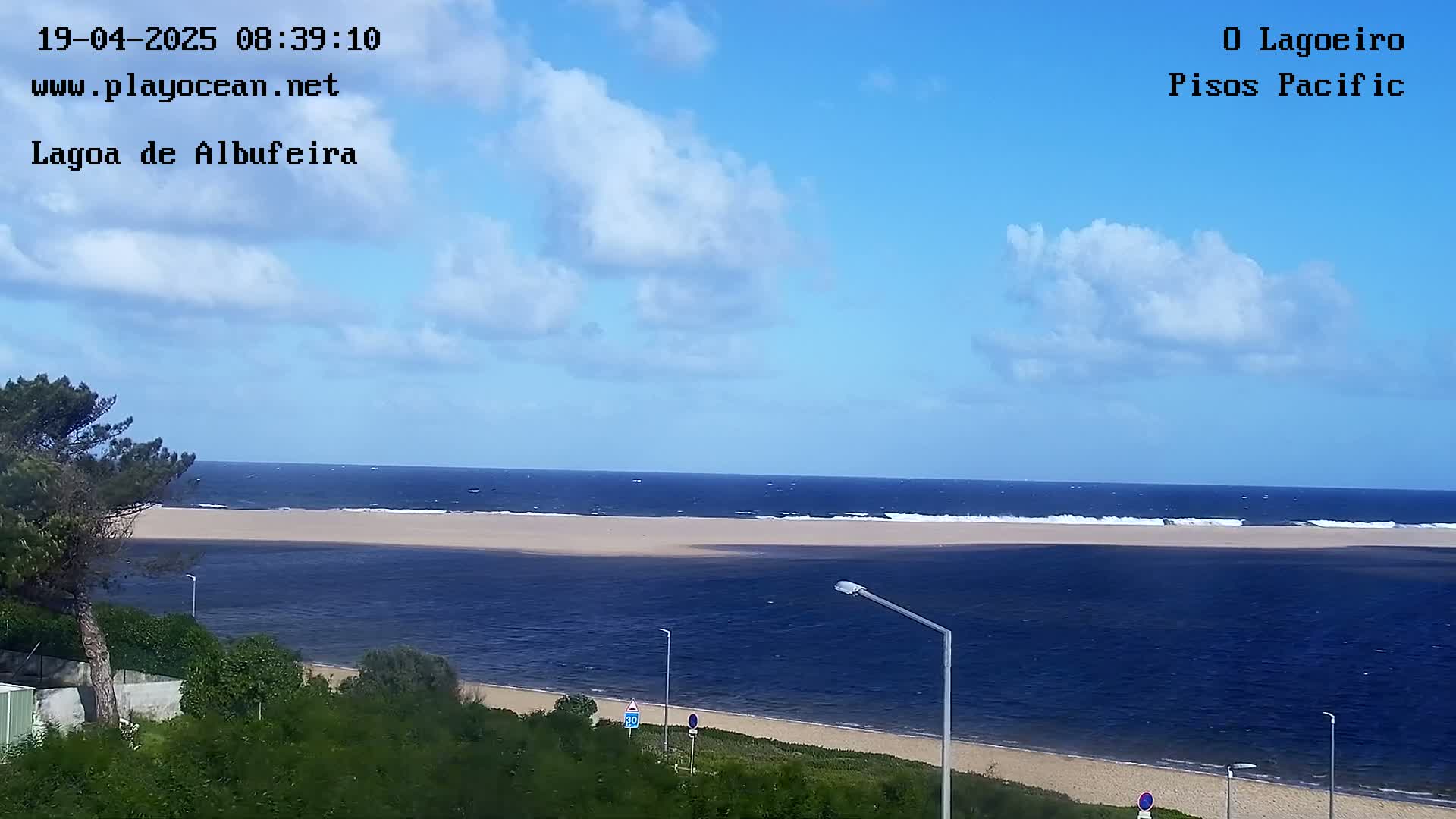 A sandy beach and calm ocean are visible under a partly cloudy sky.