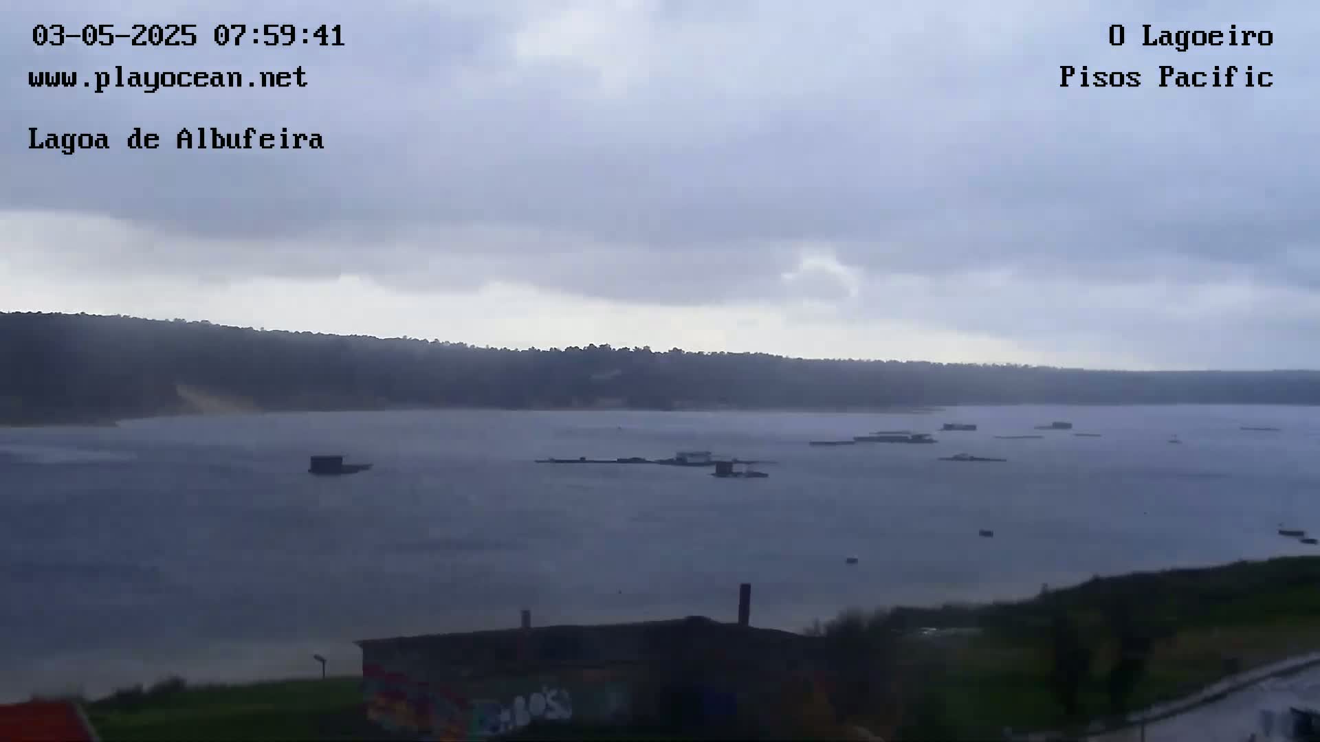 A body of water with several small structures and boats is visible under an overcast sky.