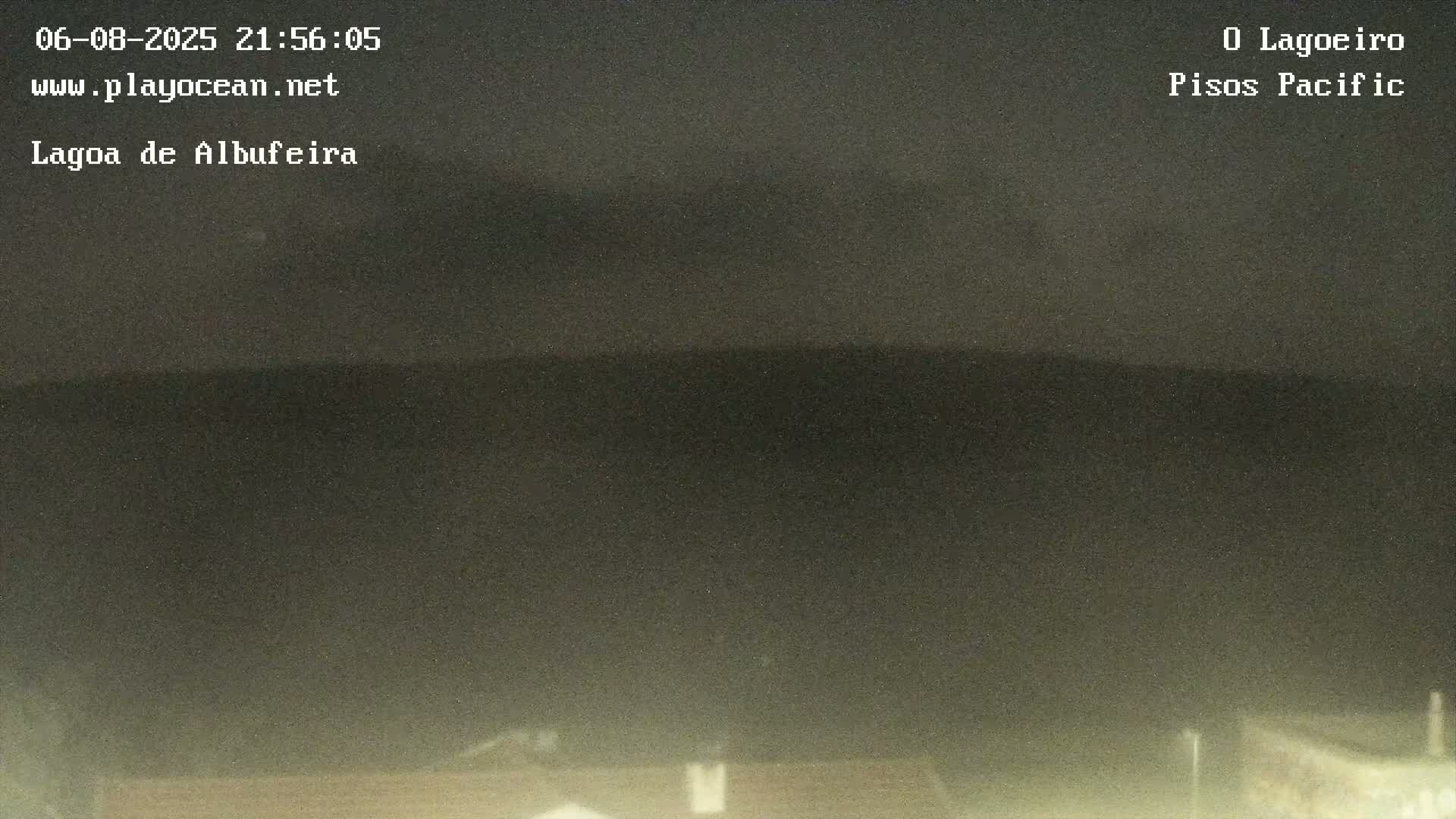 A nighttime, overcast view shows dark hills or mountains in the distance and the tops of buildings at the bottom.