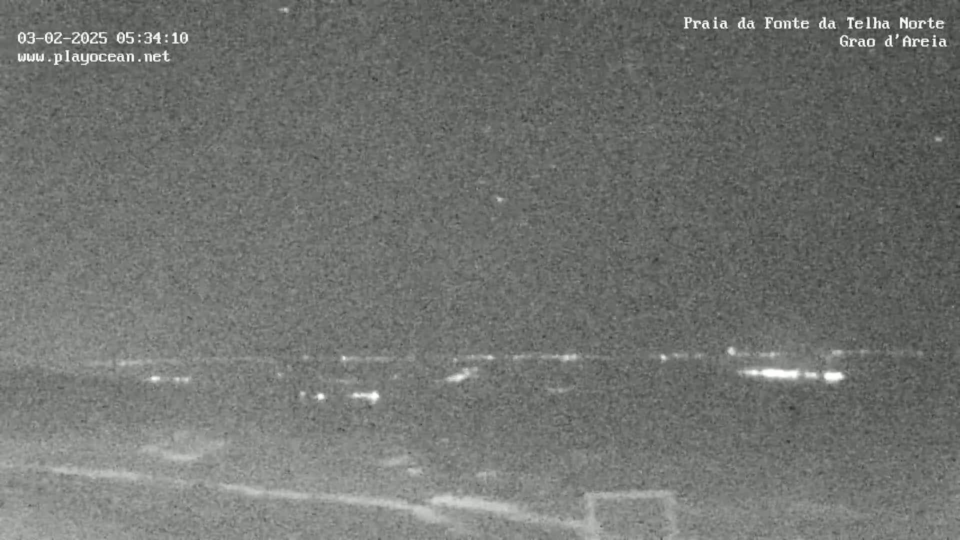 A nighttime, low-light view of a distant line of lights, possibly a town or city, stretching across the horizon.