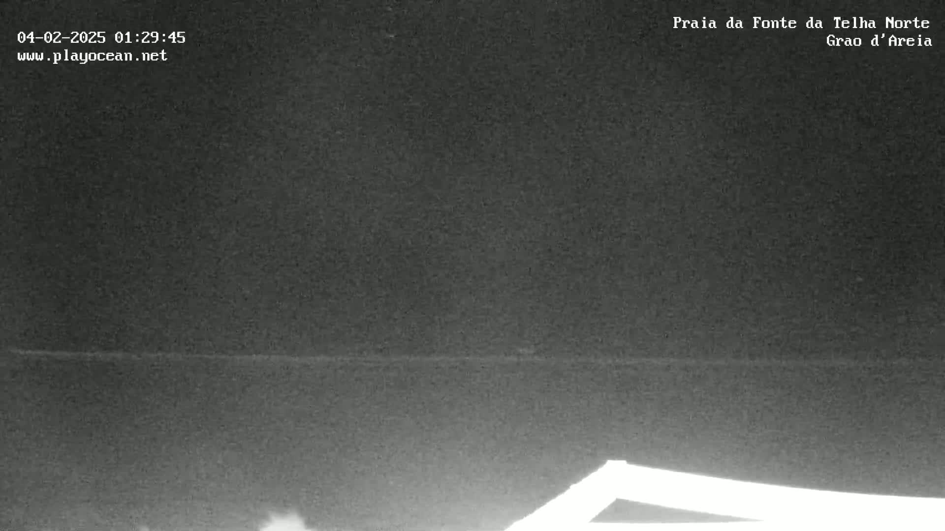 A dark, nighttime image shows a dark body of water with a faint horizon line, and a bright, possibly metallic object in the lower right corner.