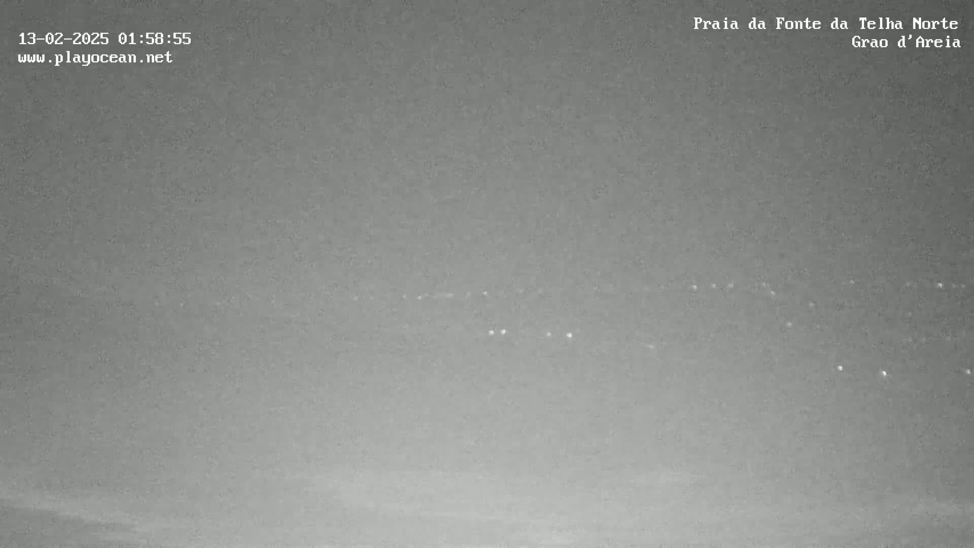 A nighttime long shot shows a line of faint lights on the horizon under an overcast sky.