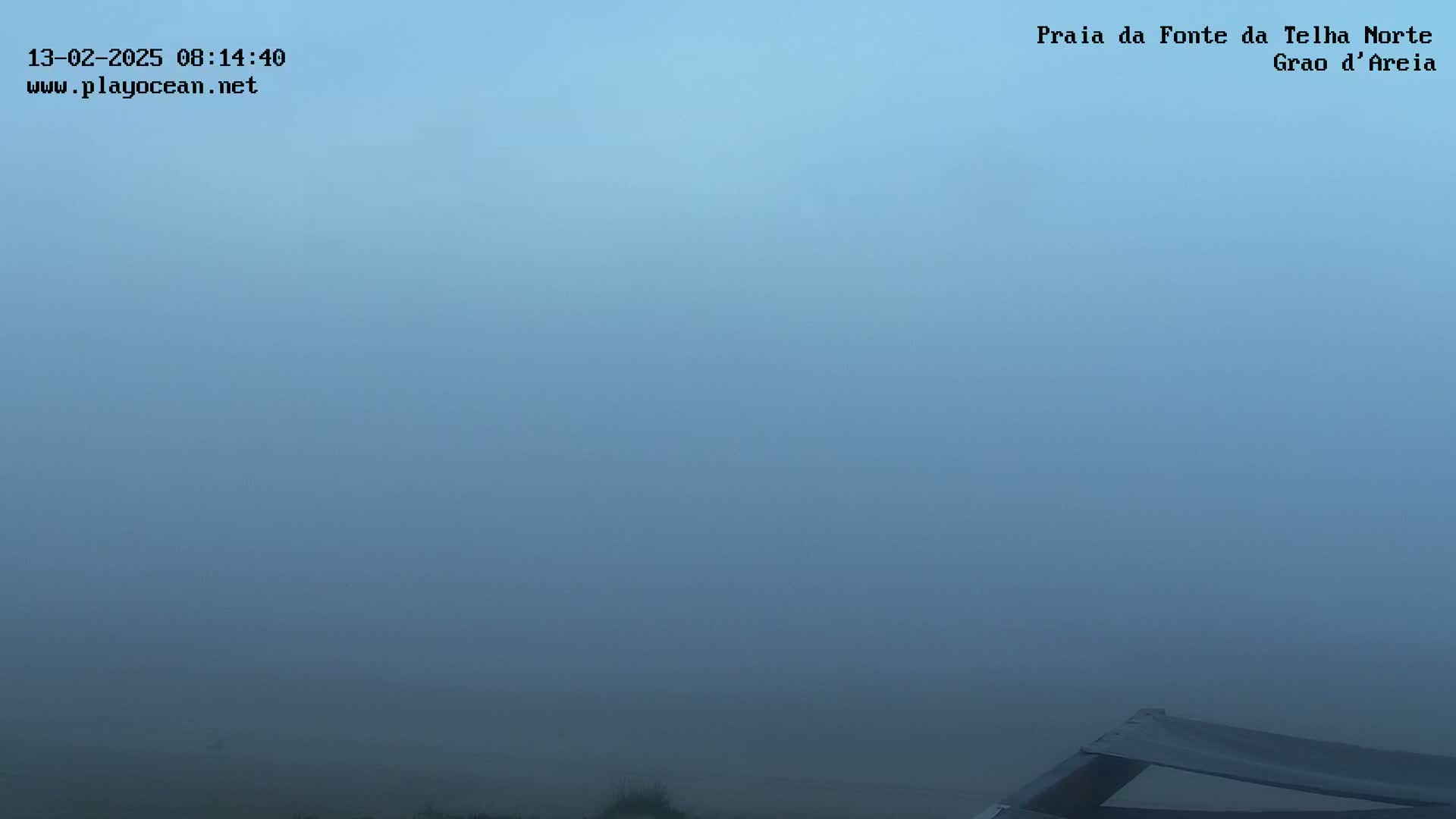 A thick fog obscures the view of a mostly empty landscape, with a portion of a dark structure visible in the bottom right corner.
