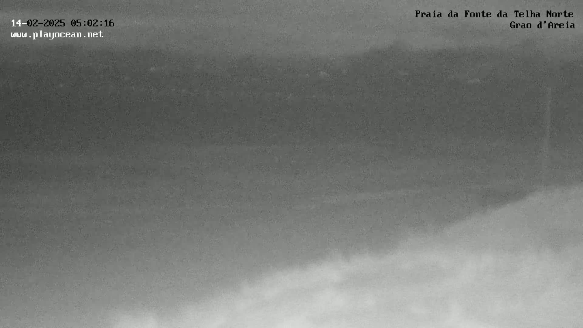 A low-light, grayscale image shows a foggy or overcast landscape with indistinct land features.