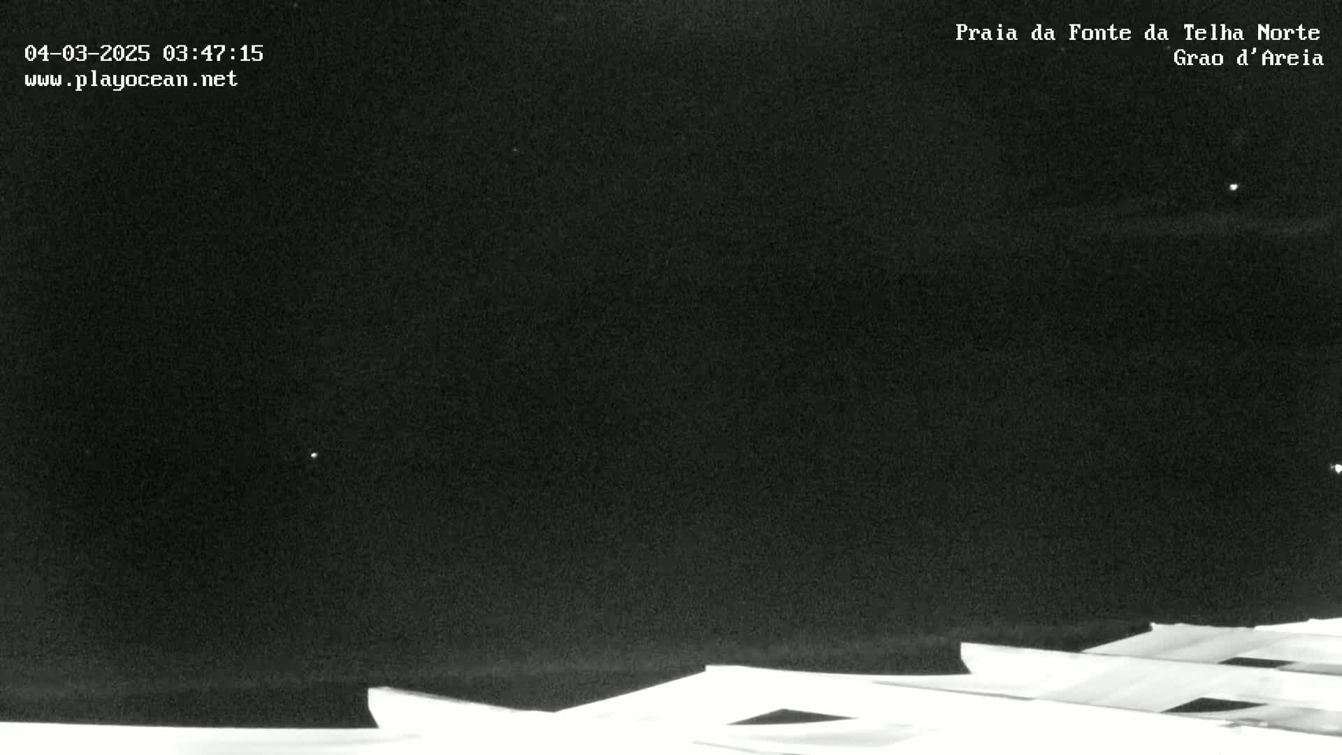 A nighttime, dark image shows the tops of several light-colored structures under a clear, starlit sky.