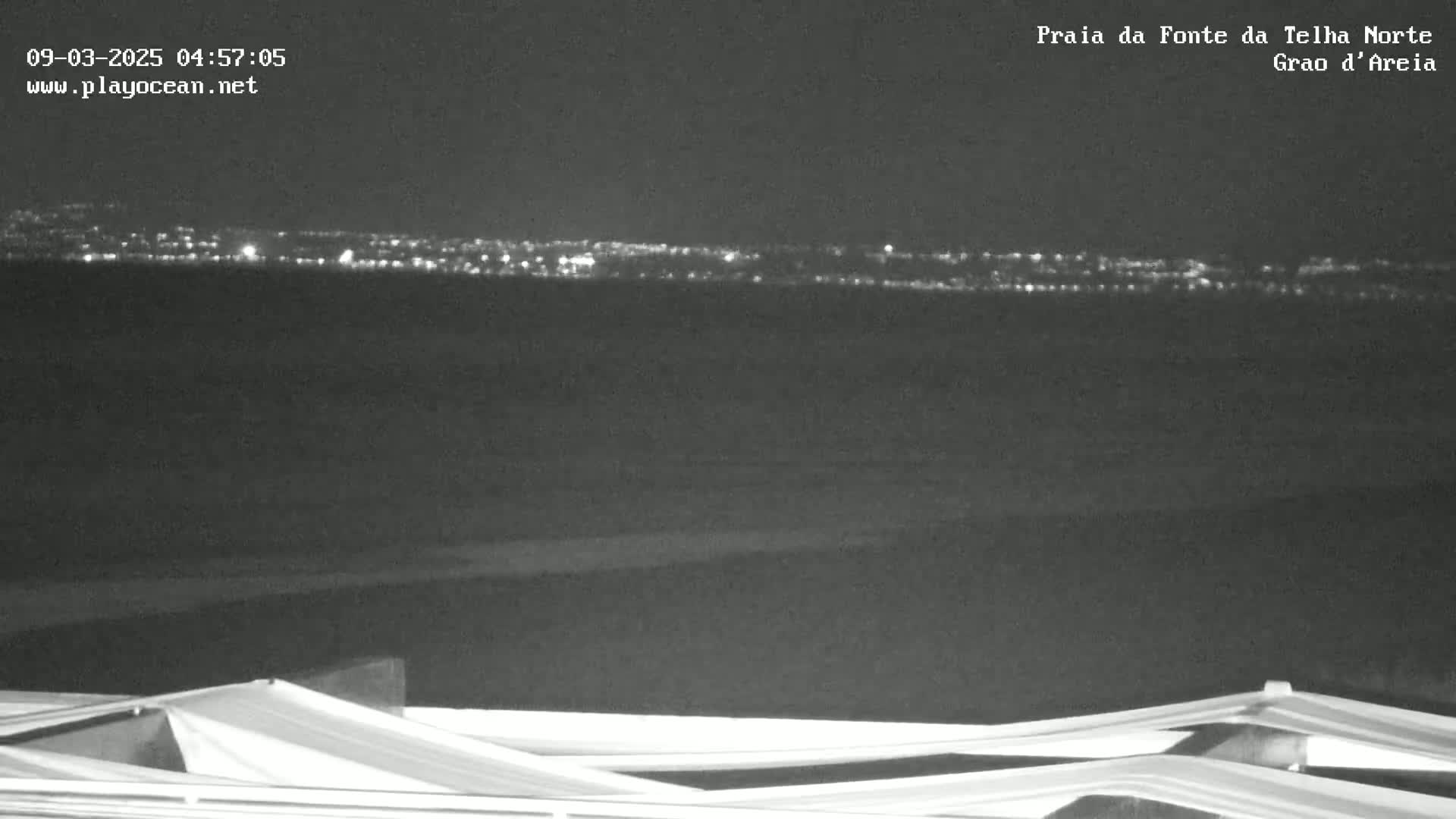 At night, a distant city skyline glows faintly on the horizon, visible above a dark foreground featuring the tops of folded structures.