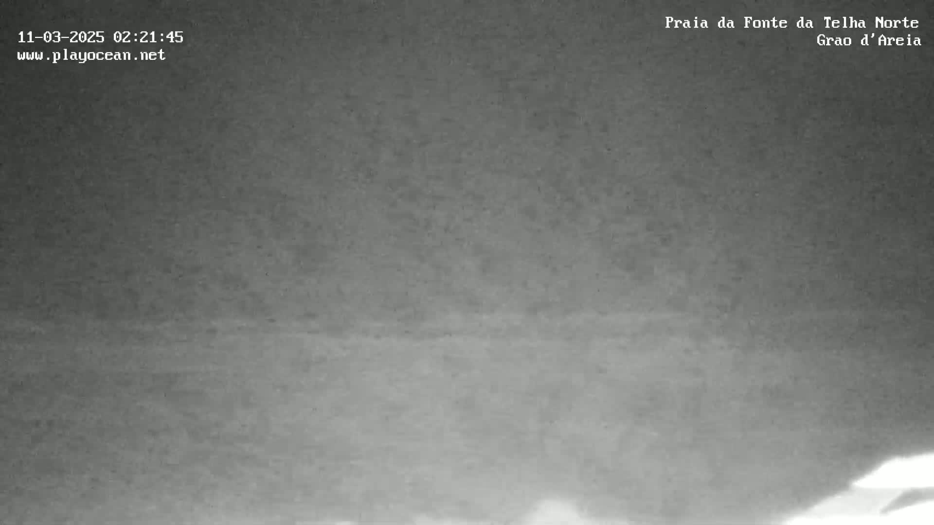 A low-light, nighttime image shows a dark, indistinct landscape.