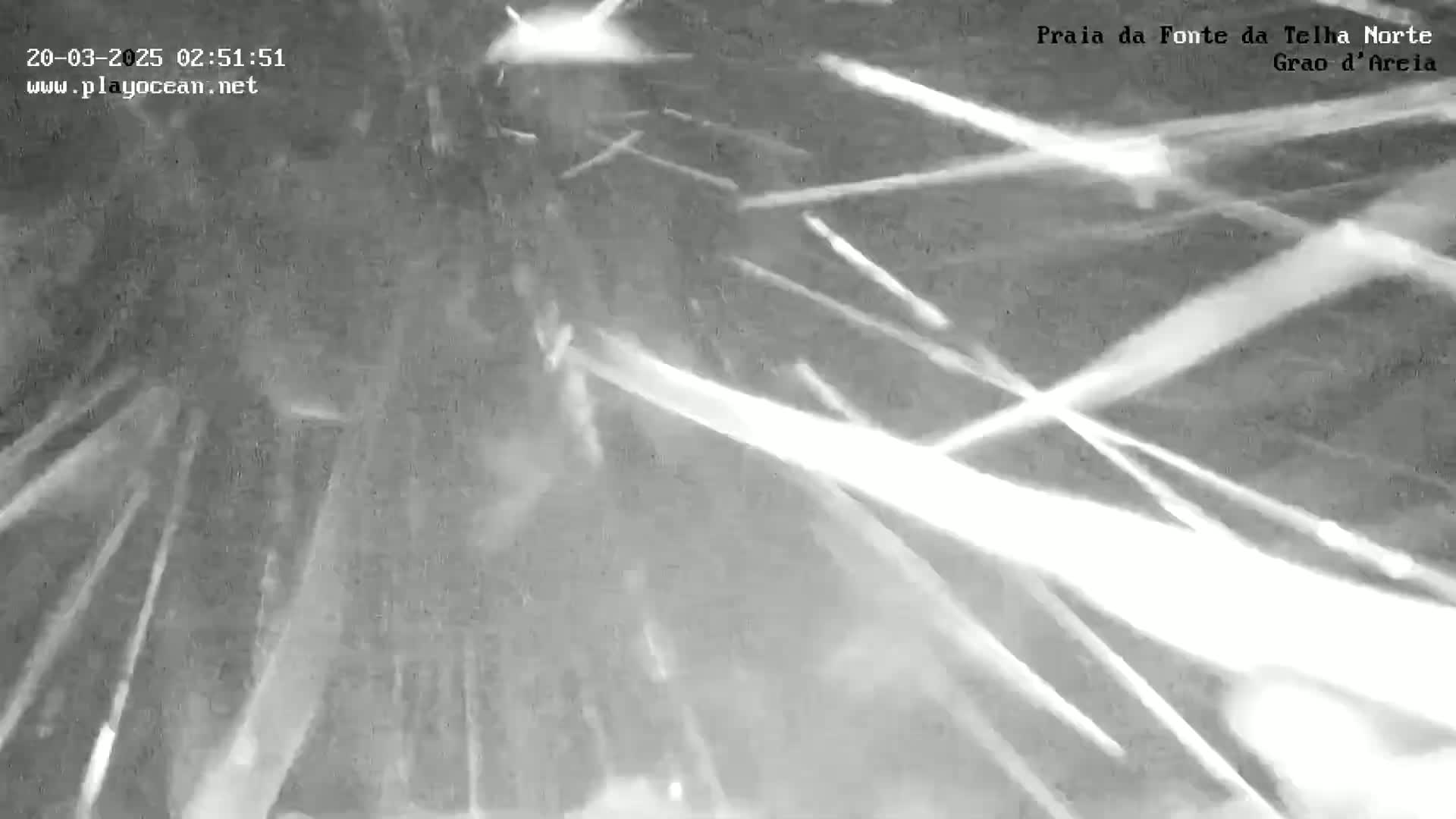 A nighttime, outdoor scene shows bright streaks of light against a dark, blurry background, suggesting strong wind or a weather phenomenon.