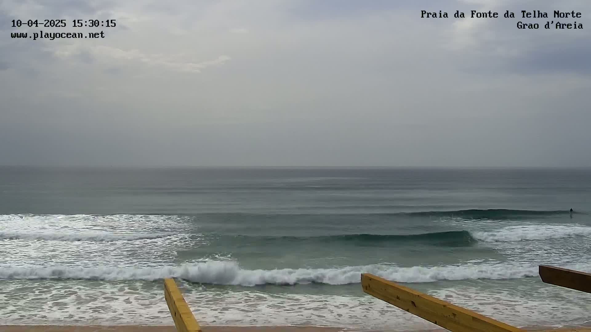 Ocean waves roll onto a sandy beach under an overcast sky.