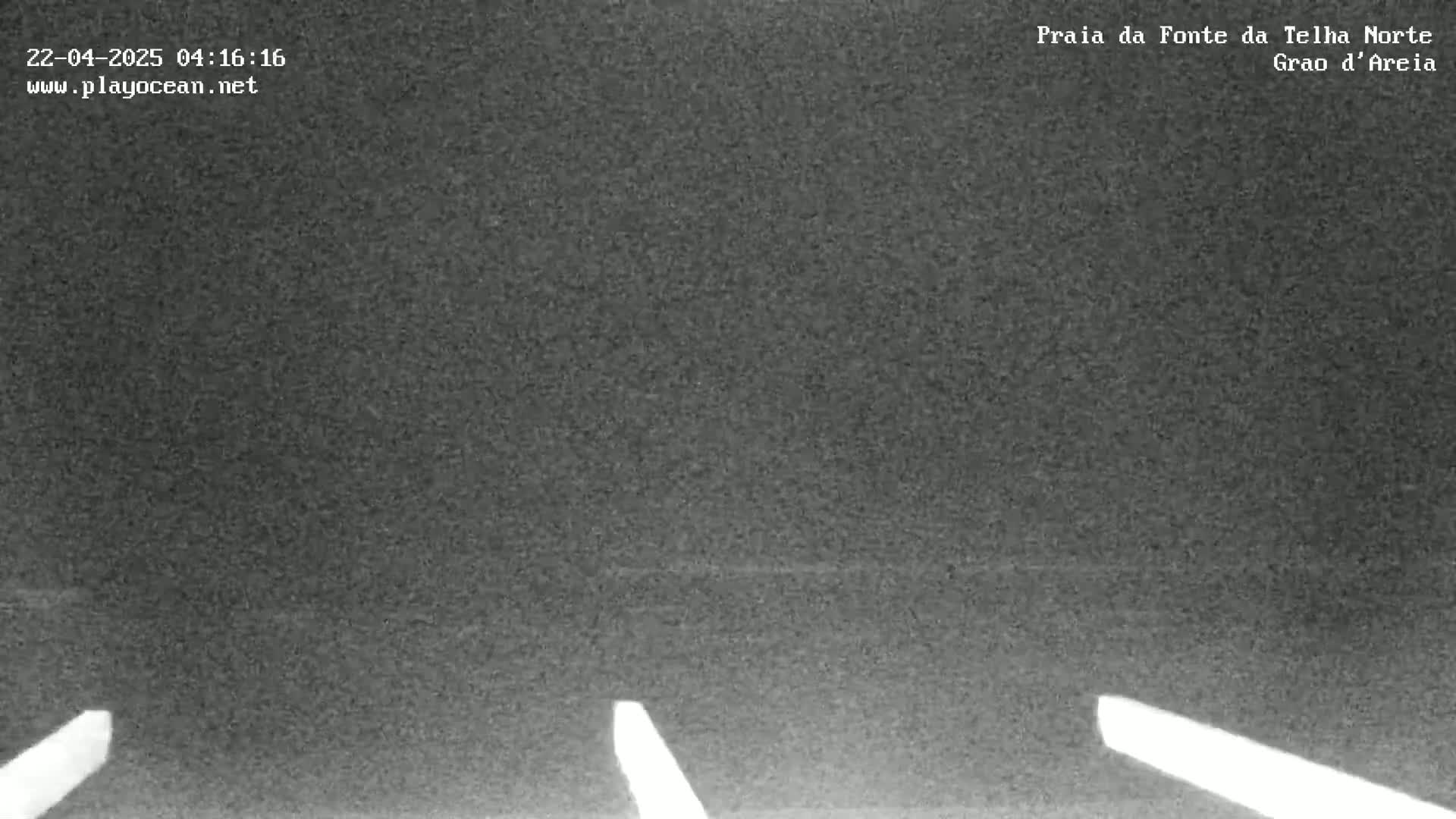 A dark, possibly nighttime, outdoor scene shows a flat, dark gray expanse with two bright, thin, vertical lines near the bottom.
