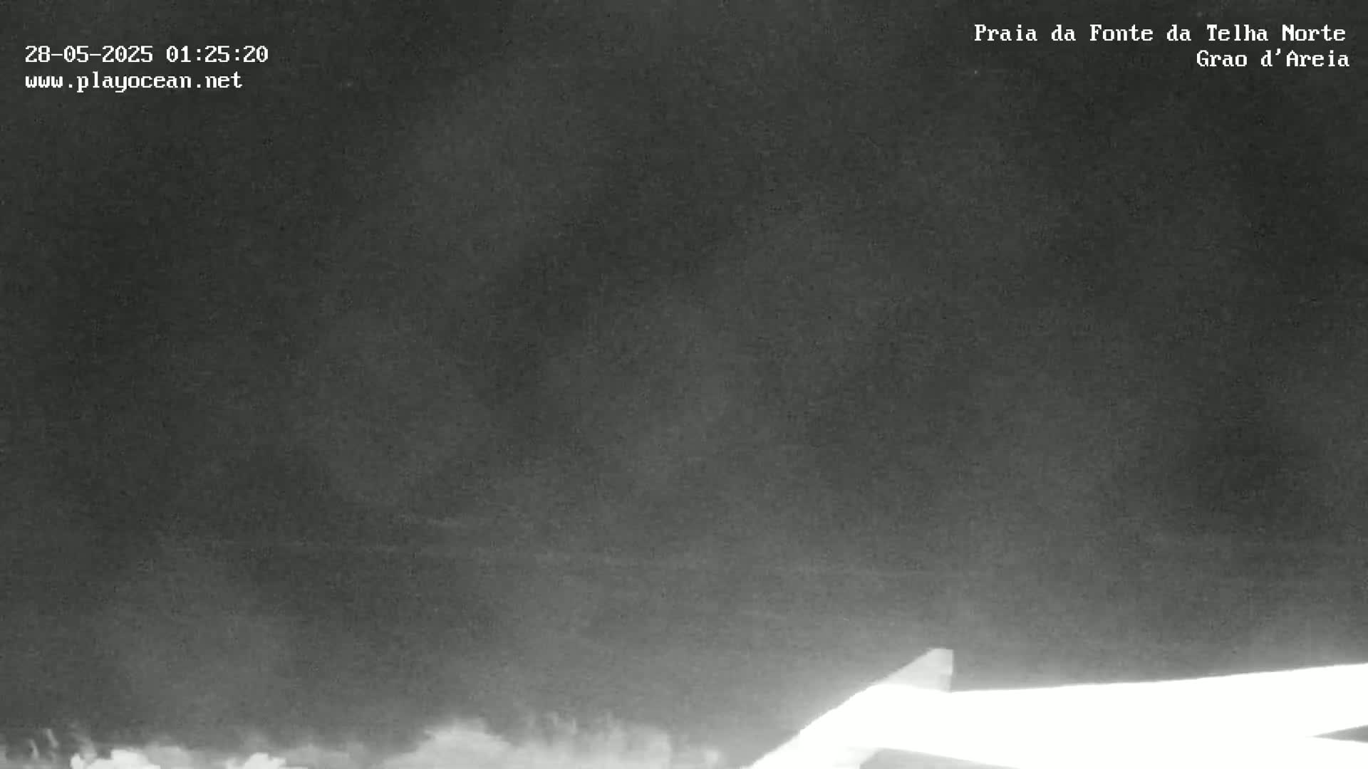 A nighttime, low-light image shows a dark, overcast sky over a beach.