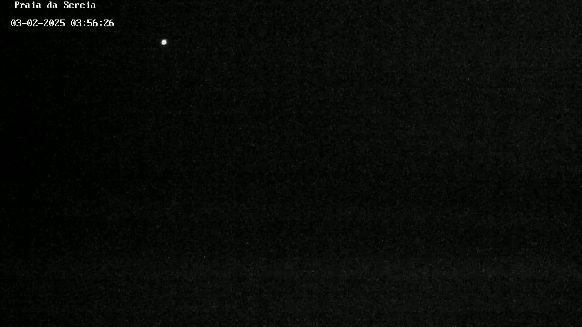 A single, bright point of light is visible in a predominantly dark, nighttime sky.