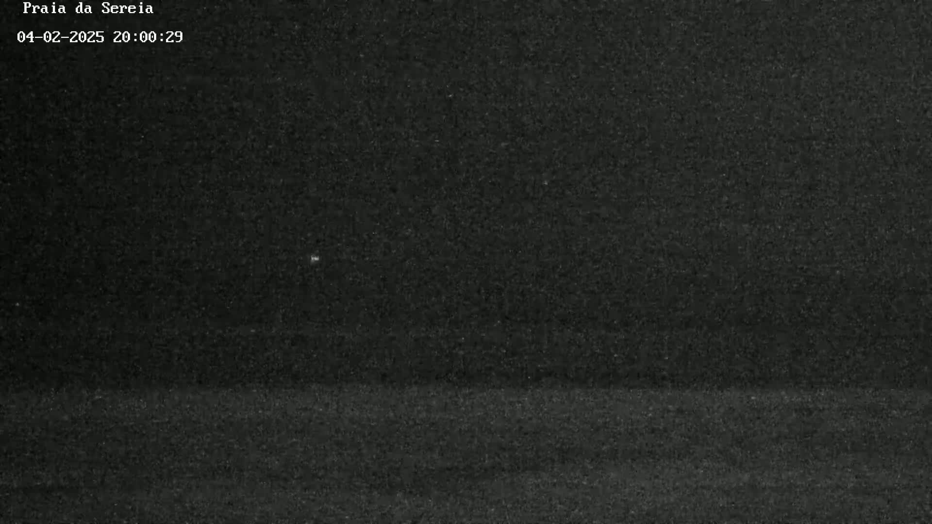 A grainy, dark image shows a mostly black sky and a dark, flat ground, possibly at night.