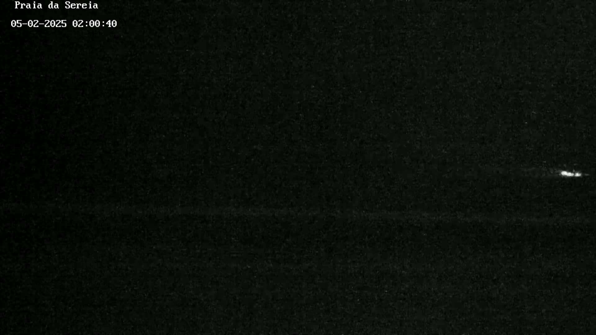 A nighttime, dark image shows a faint horizontal line near the bottom and a brighter speck of light near the top right.