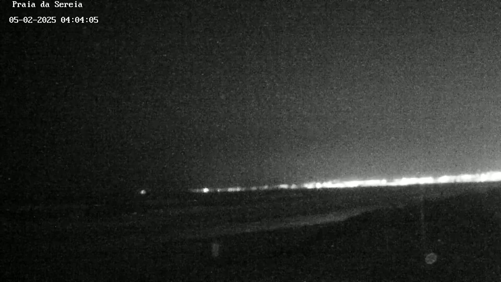 A low-light, nighttime view shows a faint line of distant lights on the horizon.