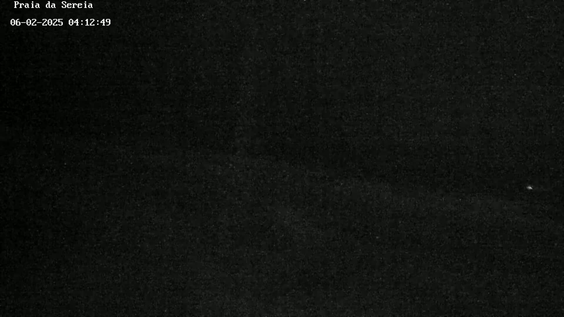 A dark, grainy image shows a mostly black scene at night.
