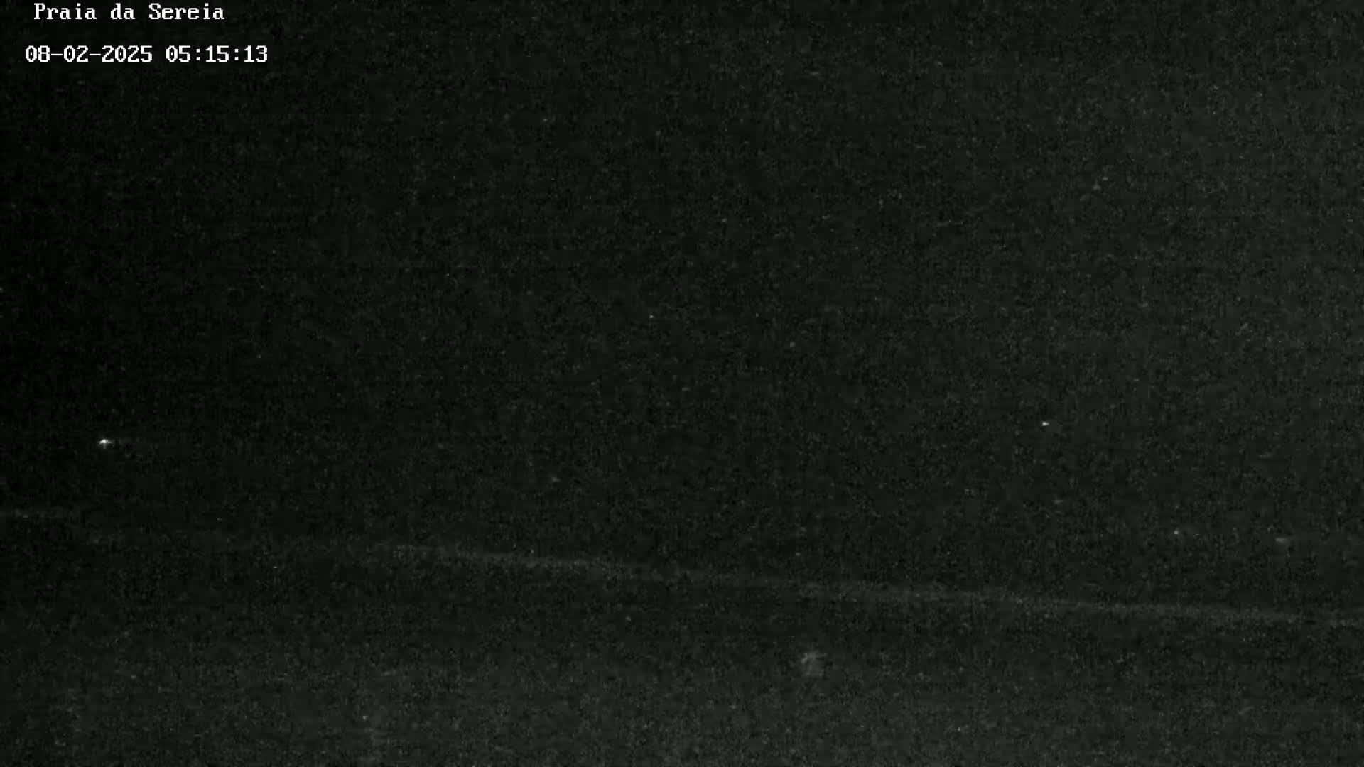 A dark, nighttime outdoor scene shows a mostly featureless black landscape with a faint horizontal line near the bottom.