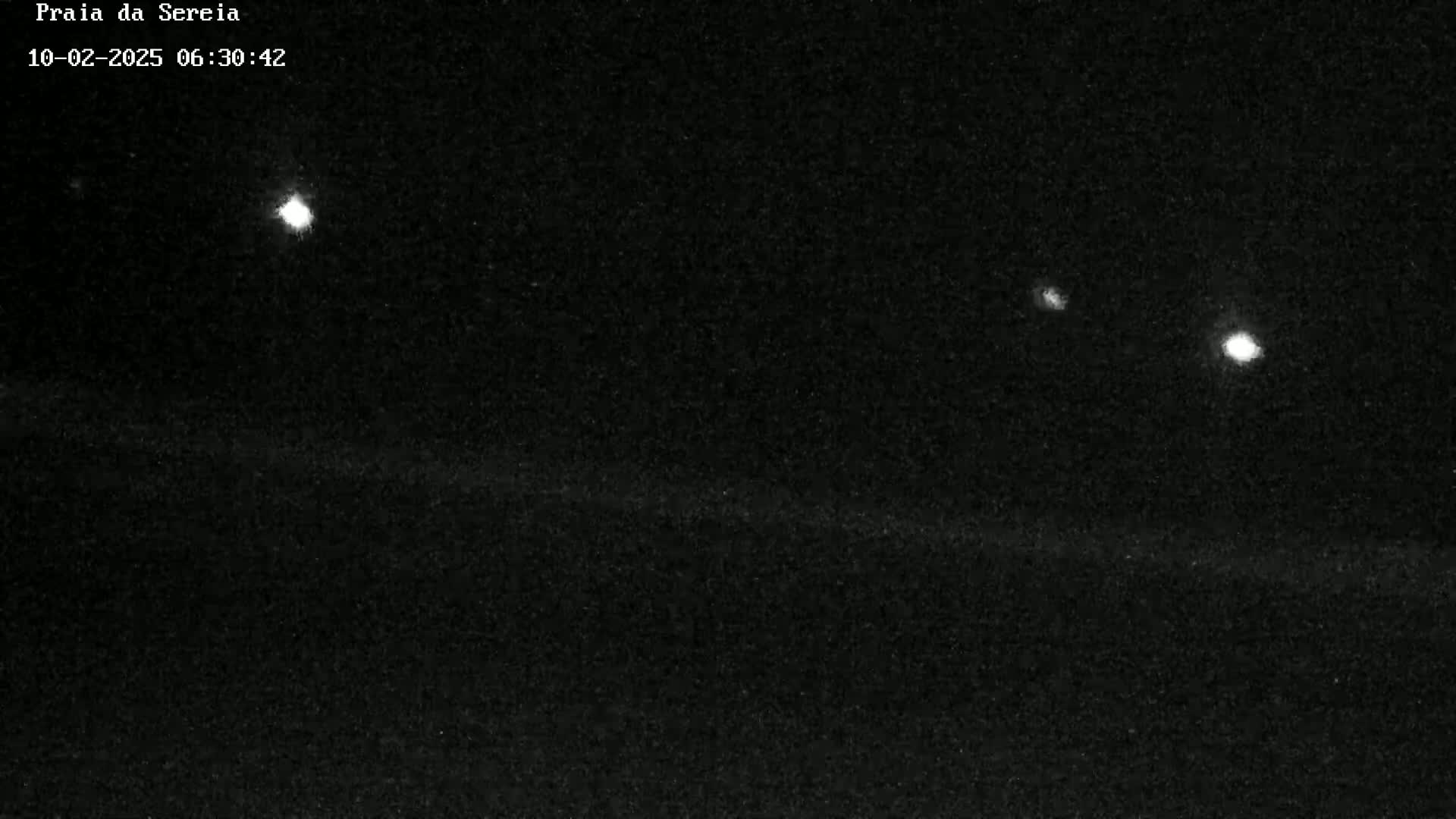 A nighttime, low-light image shows three bright lights in the dark sky above a dark, horizontal ground.