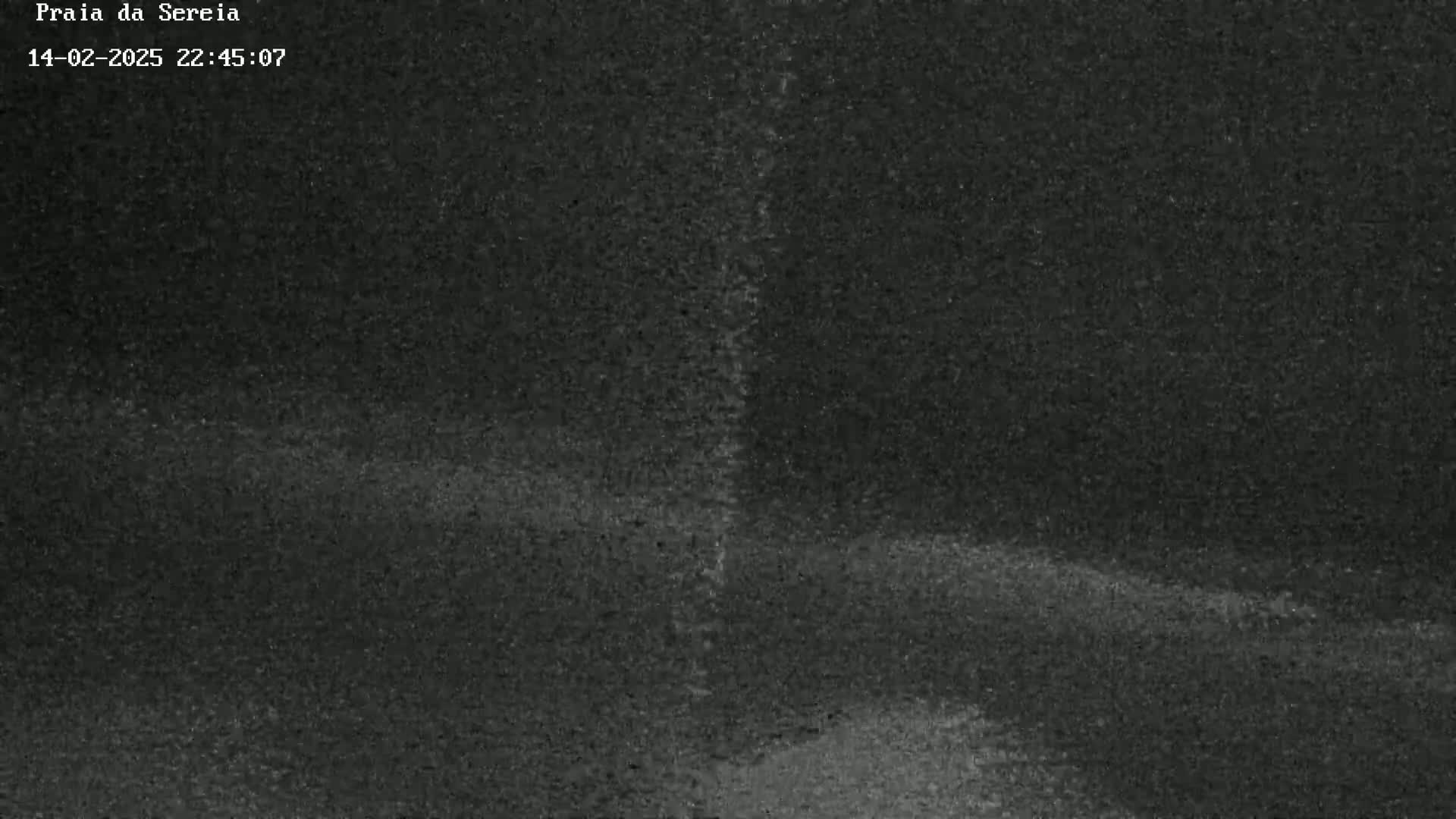 A grainy, dark nighttime image shows a mostly flat, dark surface with subtle undulations.