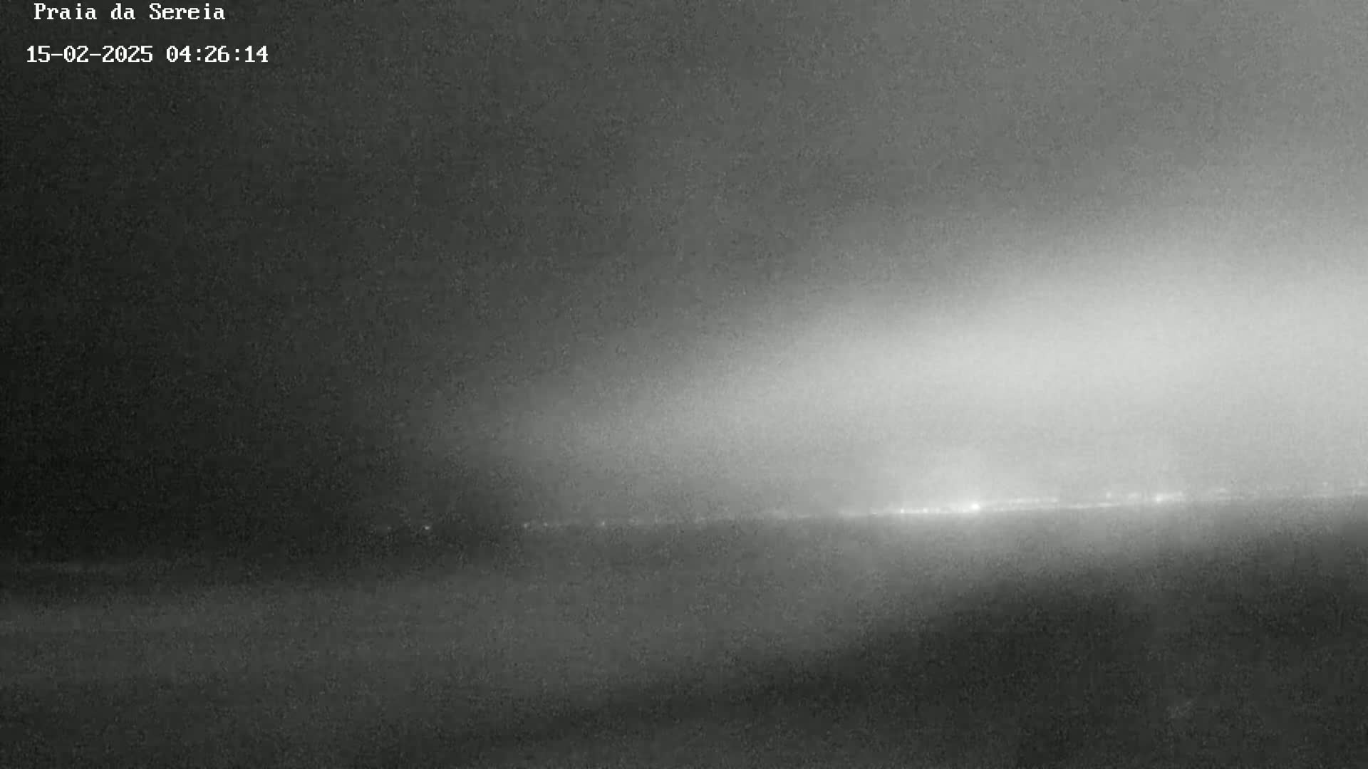 A nighttime, hazy view shows a distant line of lights on the horizon.