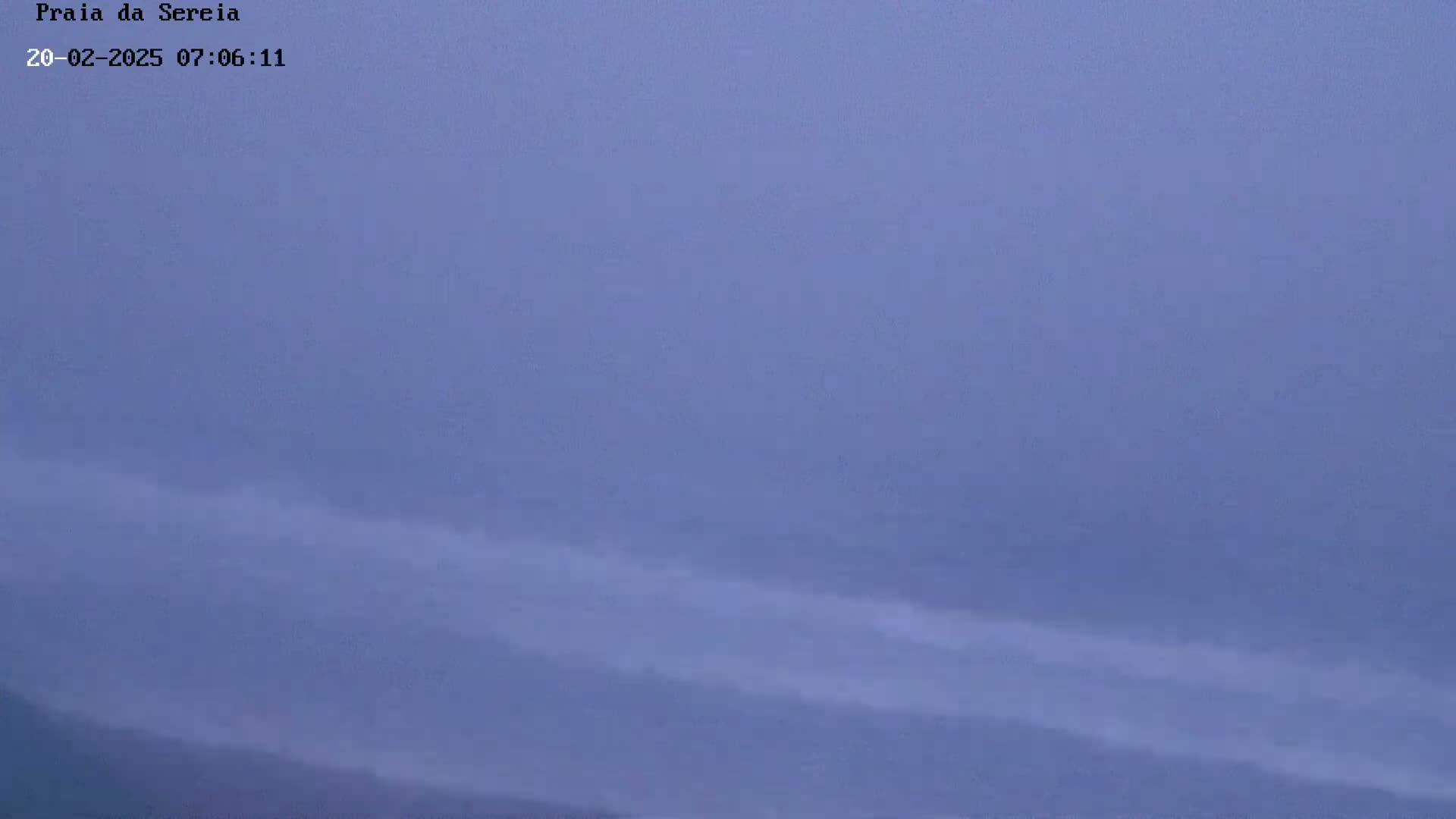 A hazy, pale blue sky shows faint, horizontal streaks of lighter color near the bottom, possibly indicating low clouds or mist.