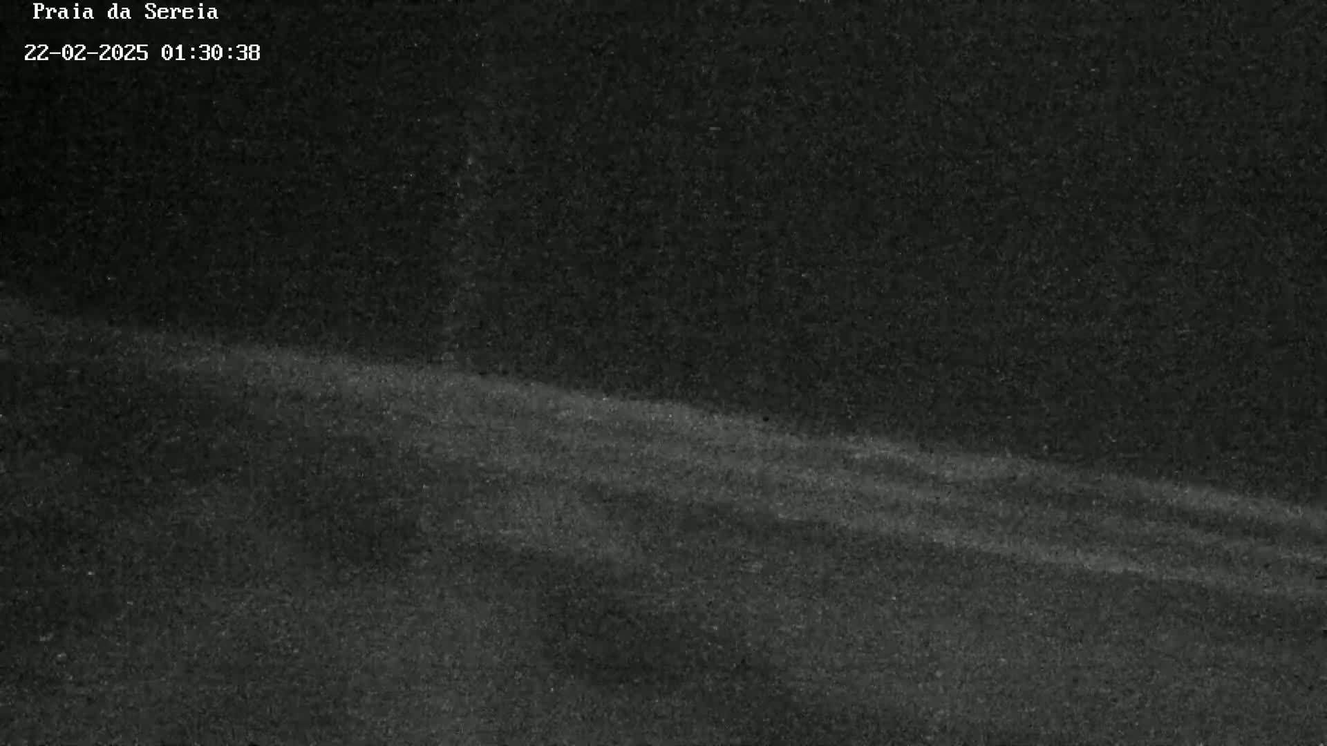 A dark, grainy image shows a gently sloping, dark surface under a night sky.