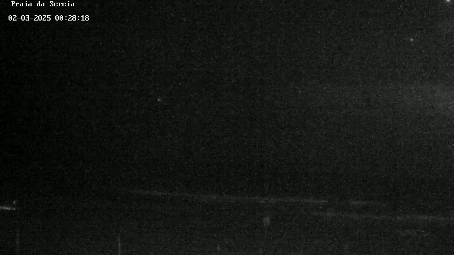A nighttime, dark, grainy image shows a mostly black sky with a barely visible horizon line.