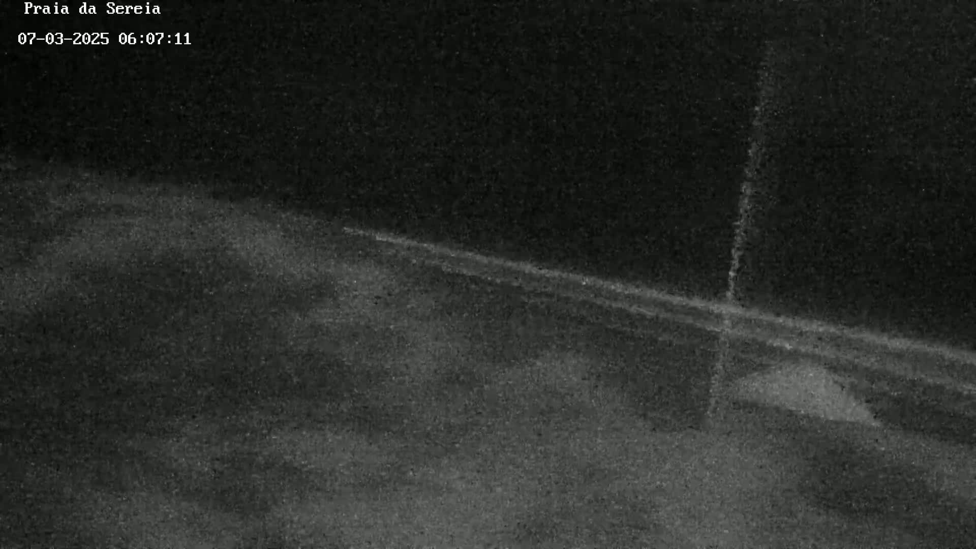 A dark, grainy nighttime image shows a road with a faint line indicating traffic.