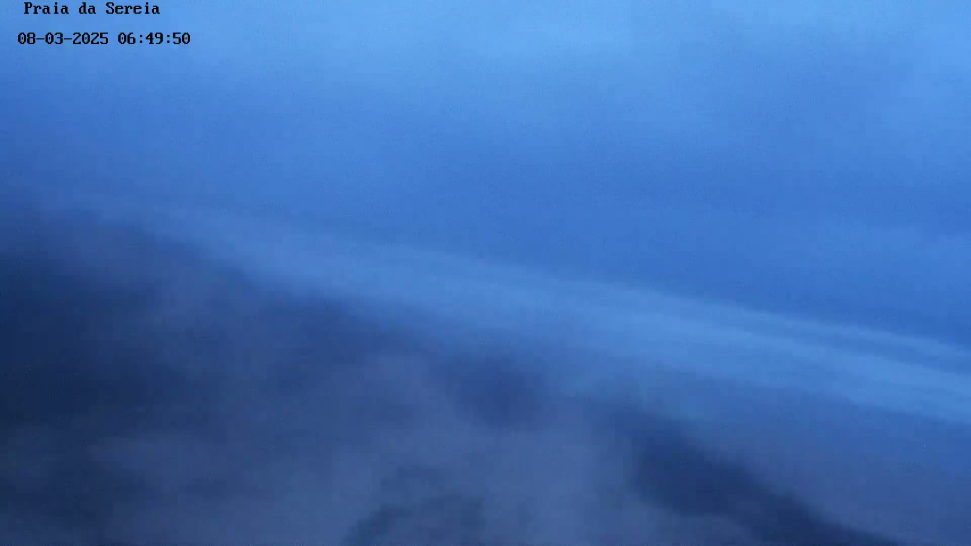A hazy, blue sky with low-lying clouds obscures the view.