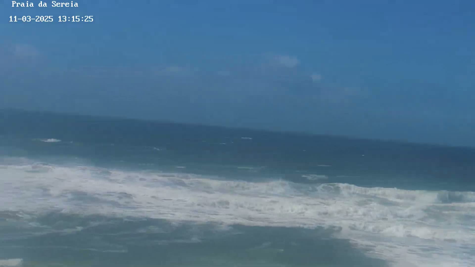 A mostly sunny day shows a wavy ocean with whitecaps under a mostly clear blue sky.