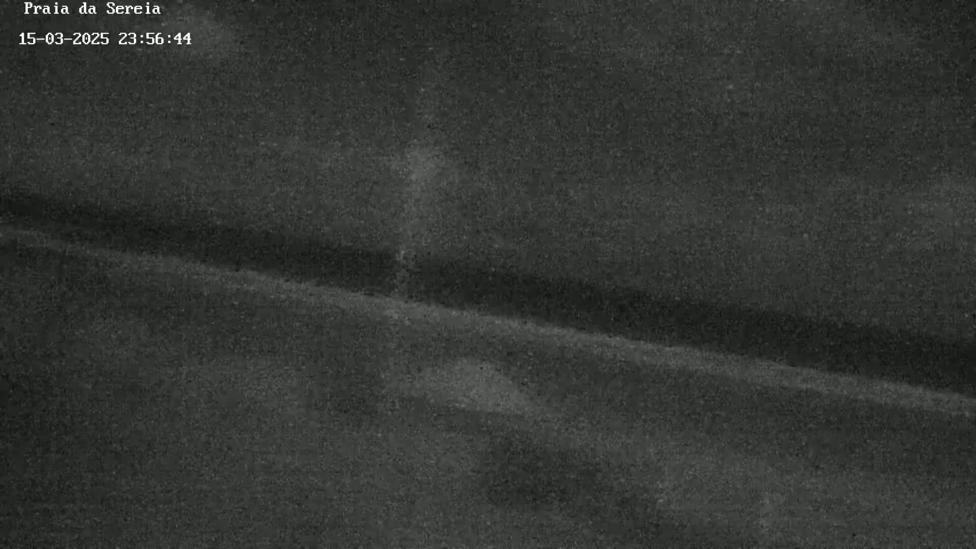 A dark, grainy image shows a gently sloping, textured surface at night.