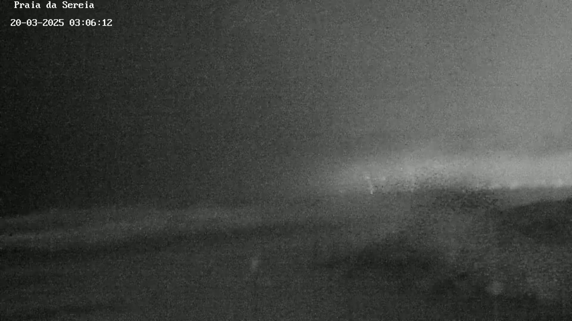A low-light, grainy image shows a dark, possibly overcast, landscape with a faint brightening horizon.